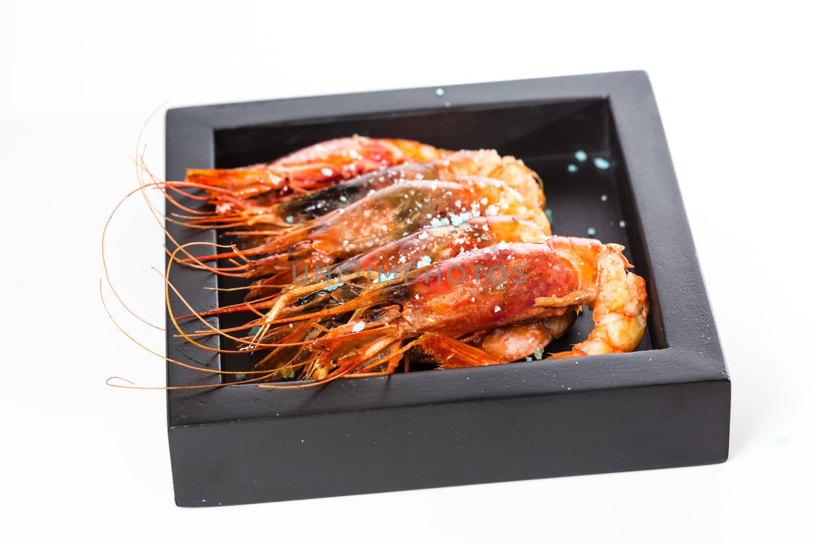 grilled shrimp in black plate on white background. by sarymsakov