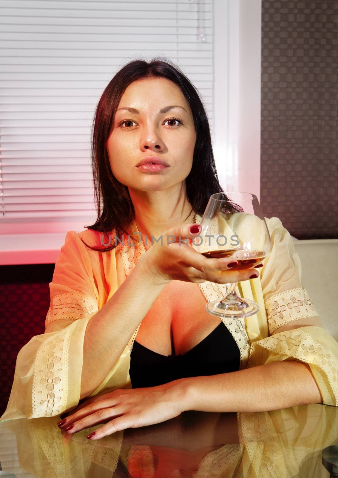 beautiful sad girl with glass of brandy in cafe