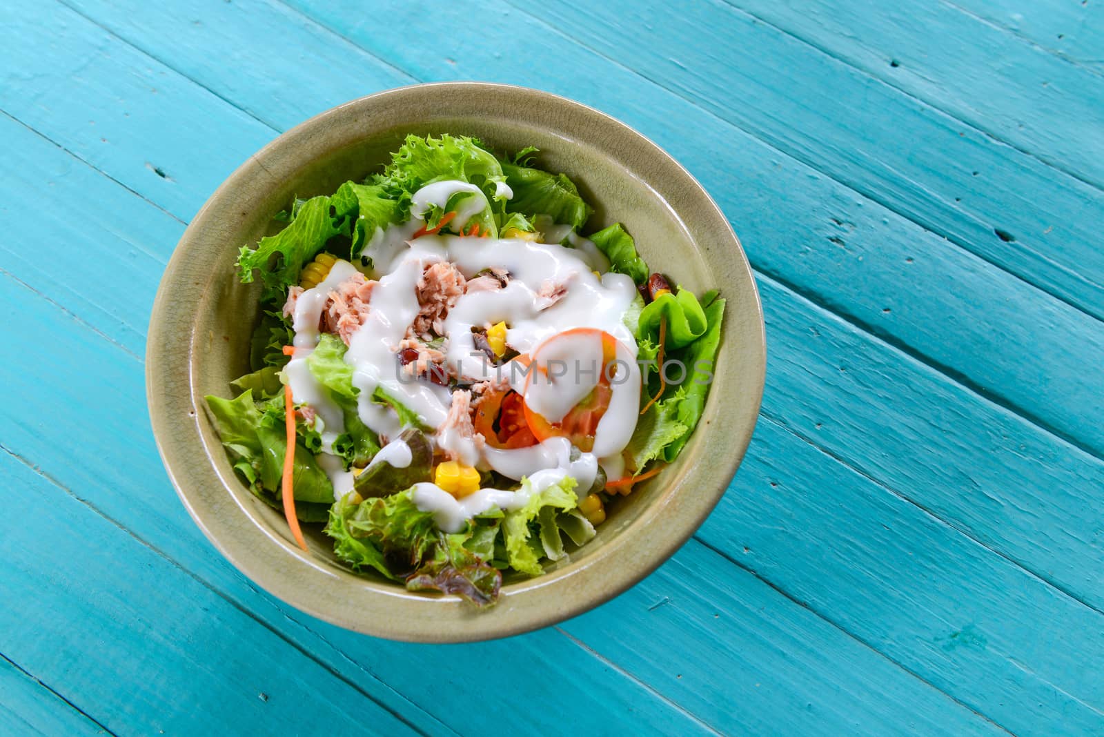 vegetable salad with tuna in a bowl on blue table