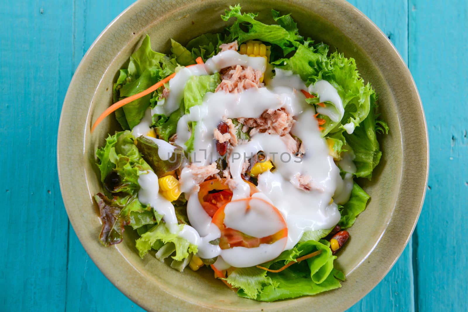 Closeup vegetable salad with tuna in a bowl on blue table