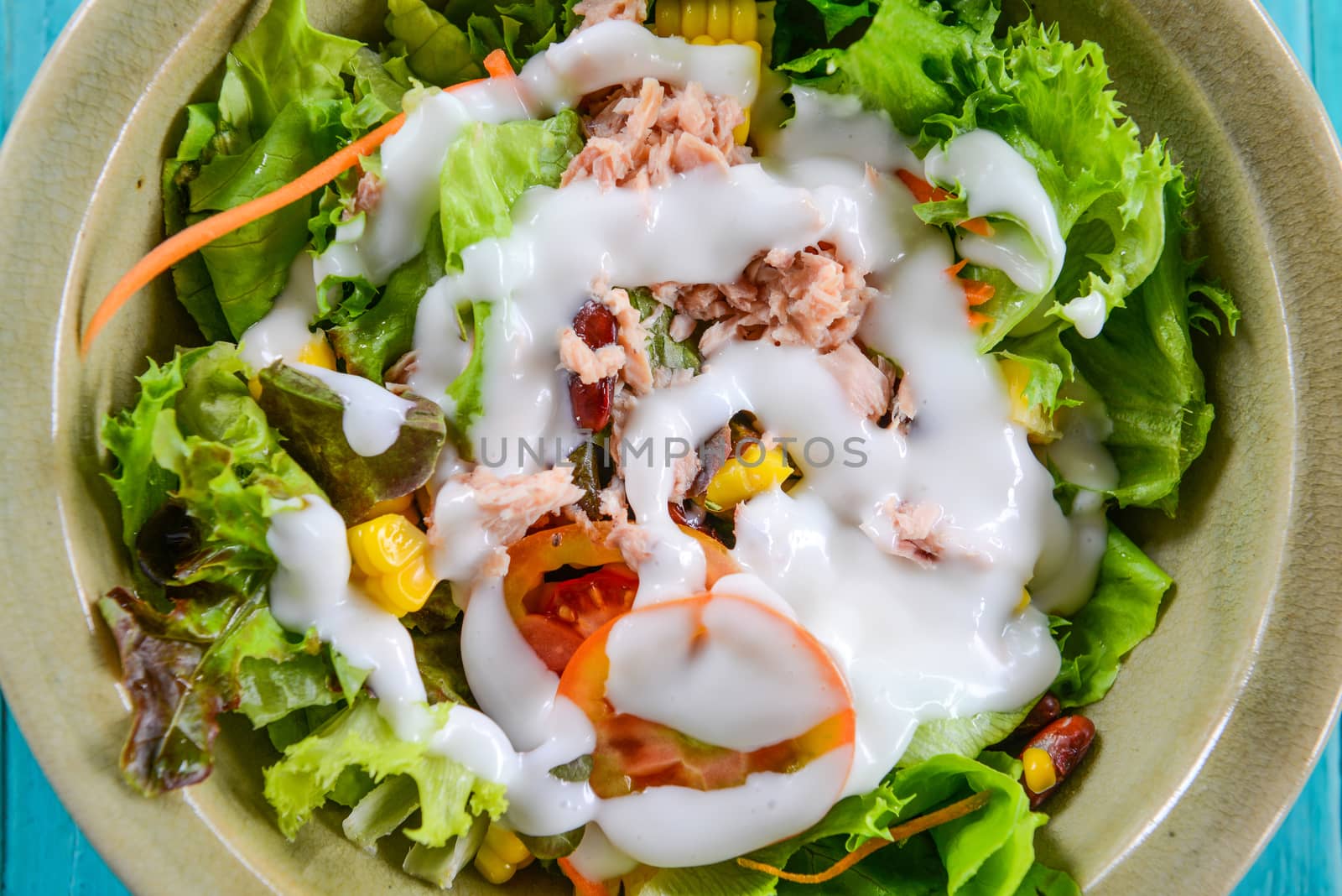 Closeup vegetable salad with tuna in a bowl on blue table