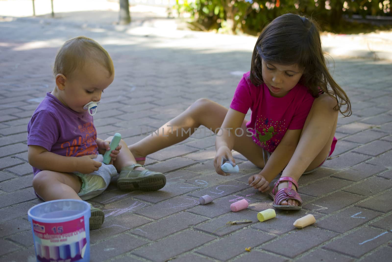 Two brothers drawing with chalk on the ground