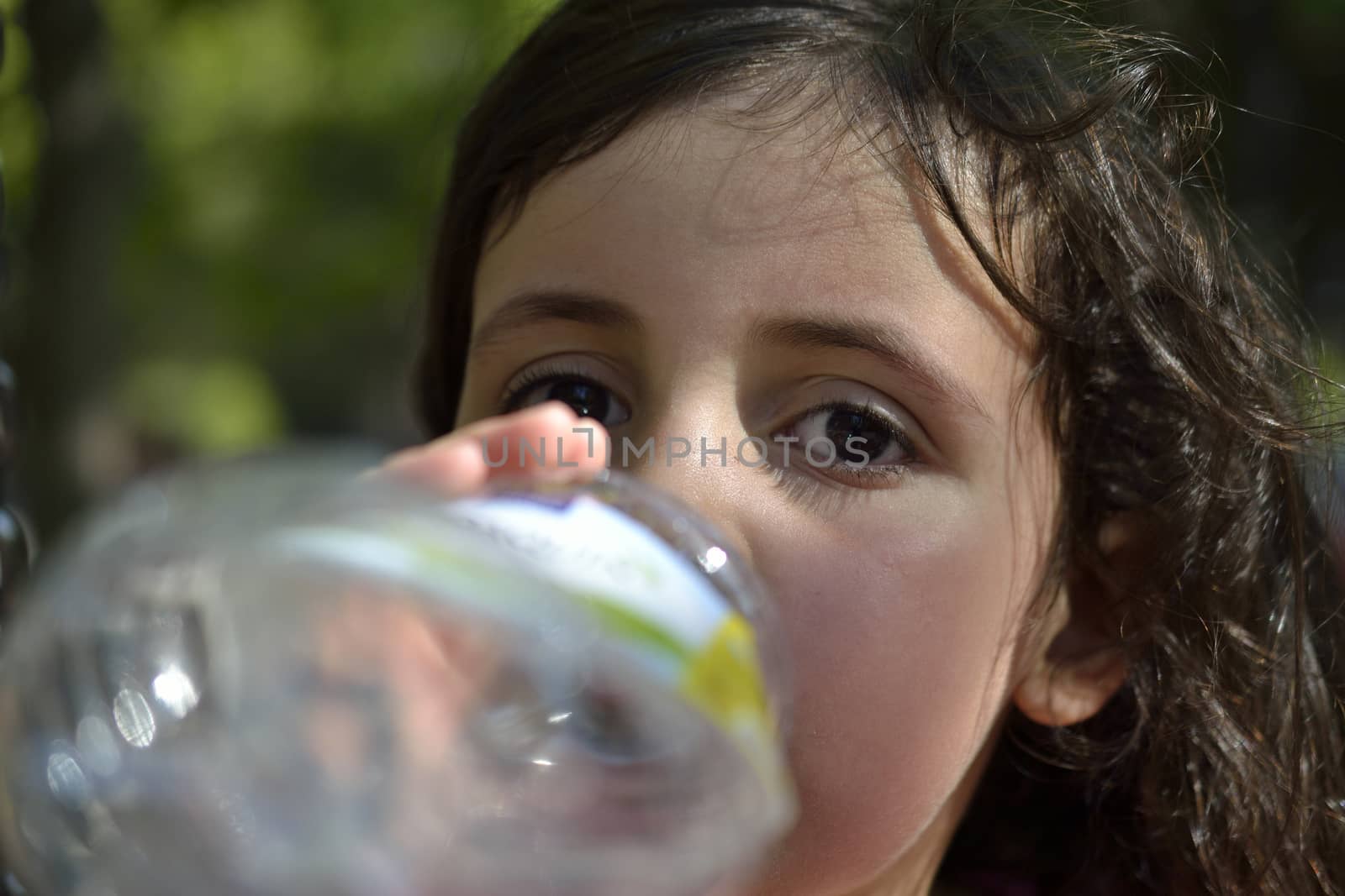little girl drinking water from a plastic bottle