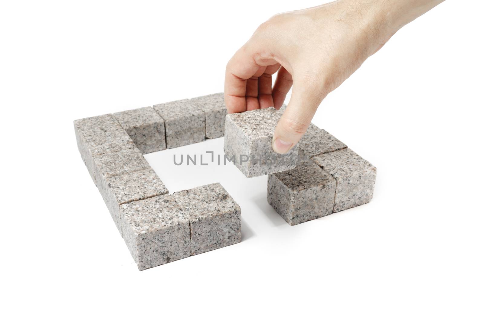 Man finishing a square made of small blocks of granite rock.