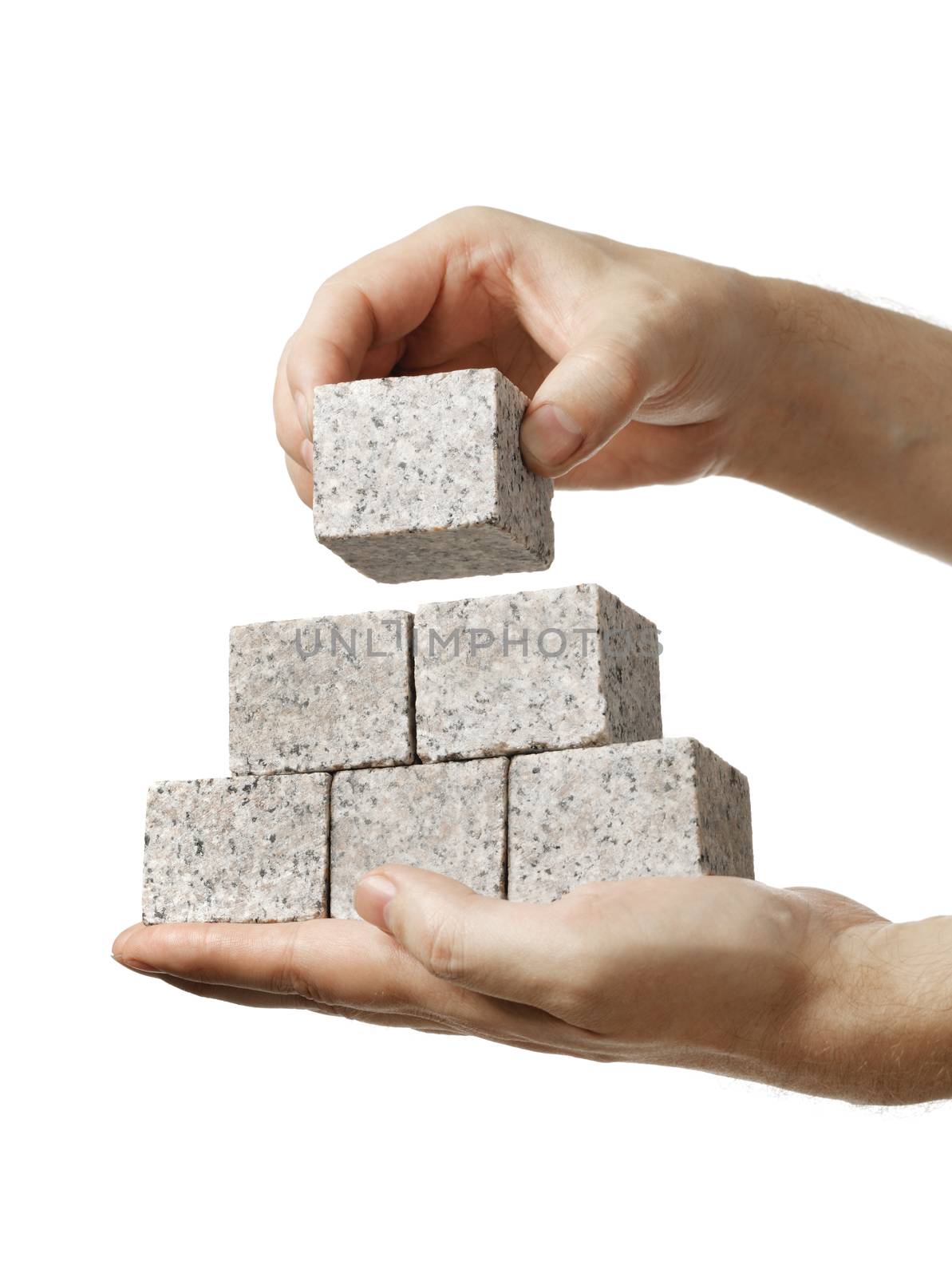 Man stacking small blocks of granite rock in his hands.