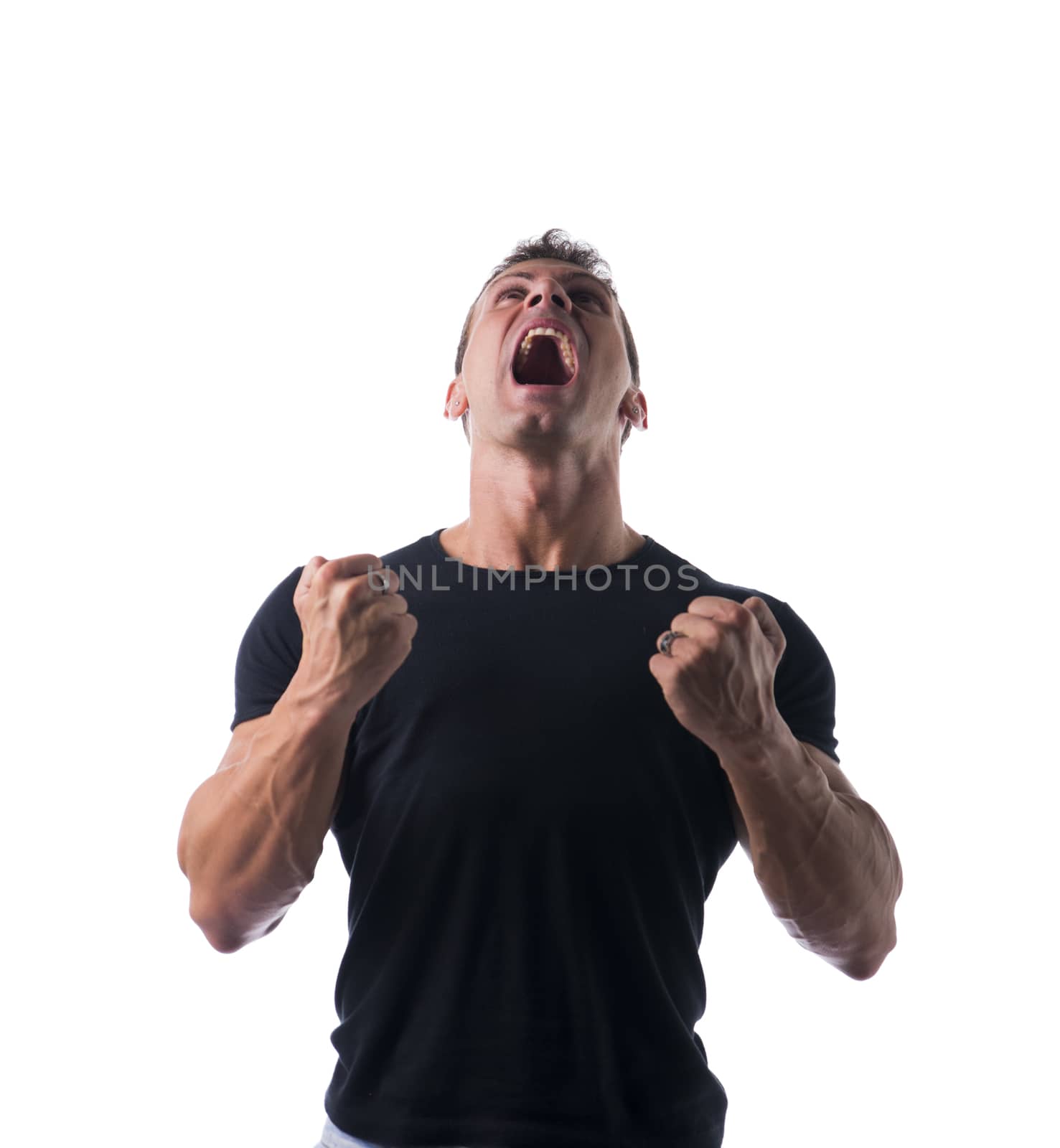 Young Angry Muscled Man, Shouting with Closed Fists, in Plain Black Shirt, Isolated on White Background.