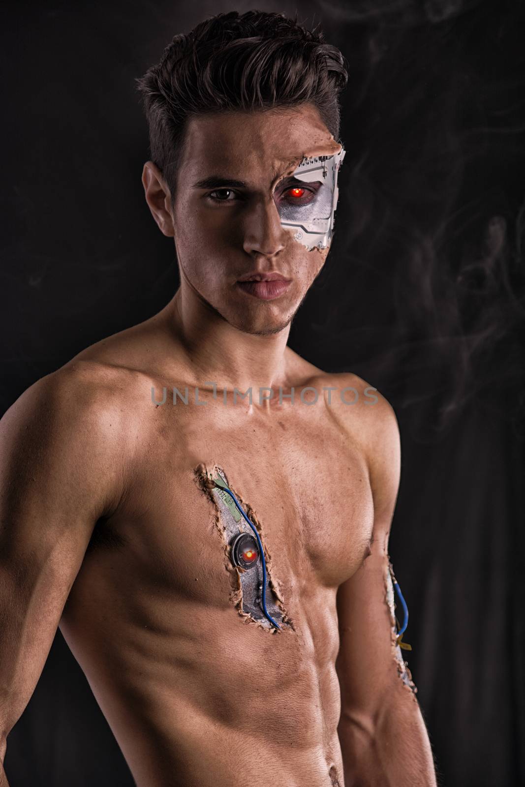 Close up Attractive Bare Muscled Man with Robotic Skin Art Looking at the Camera on Black Background.