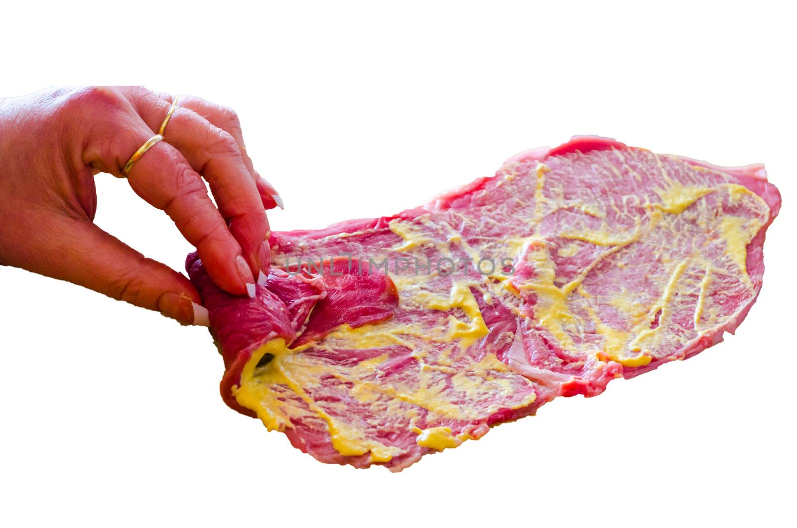 Woman hand rolls a beef roulade in front of white background
