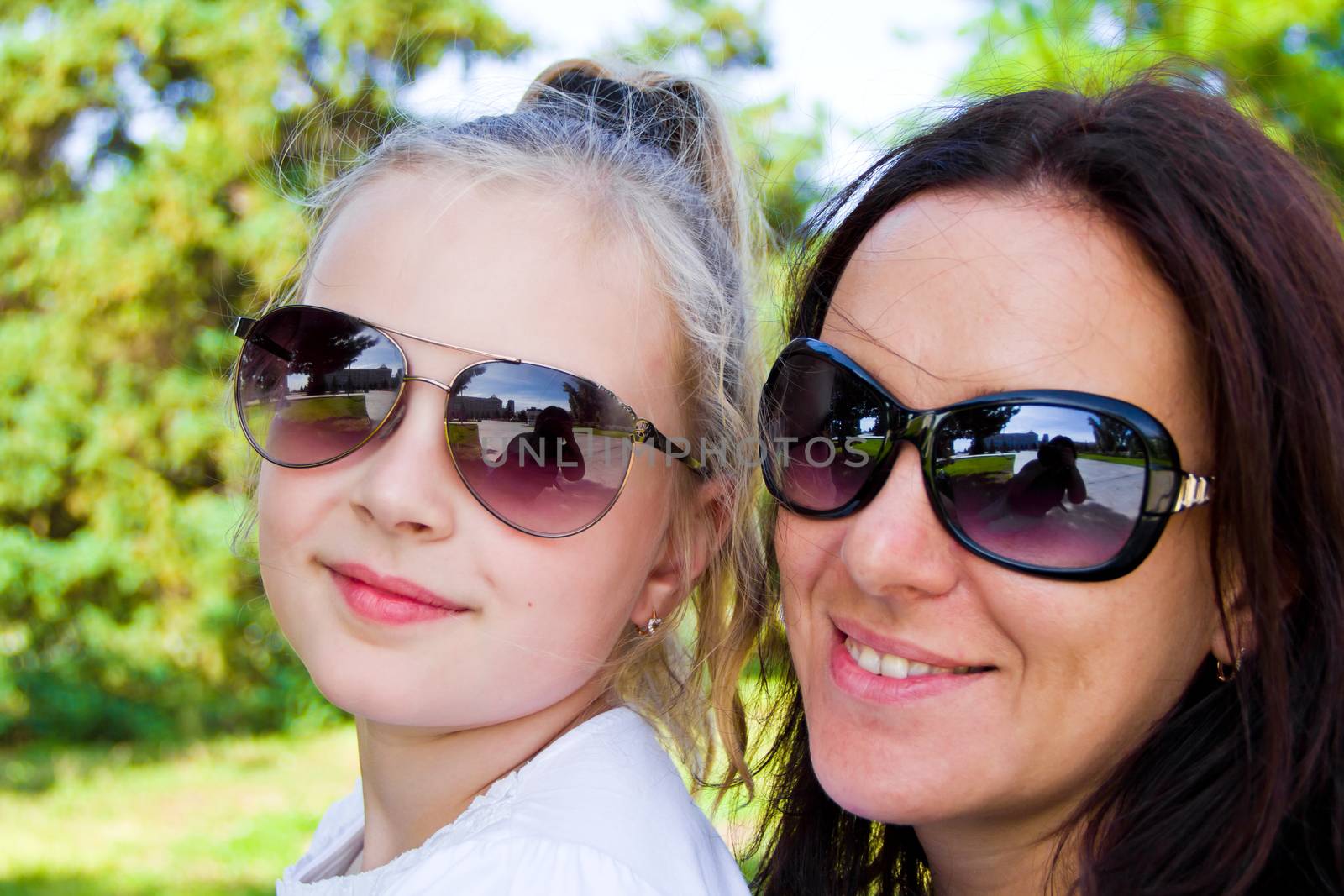 Photo of smiling mother and daughter in sunglasses