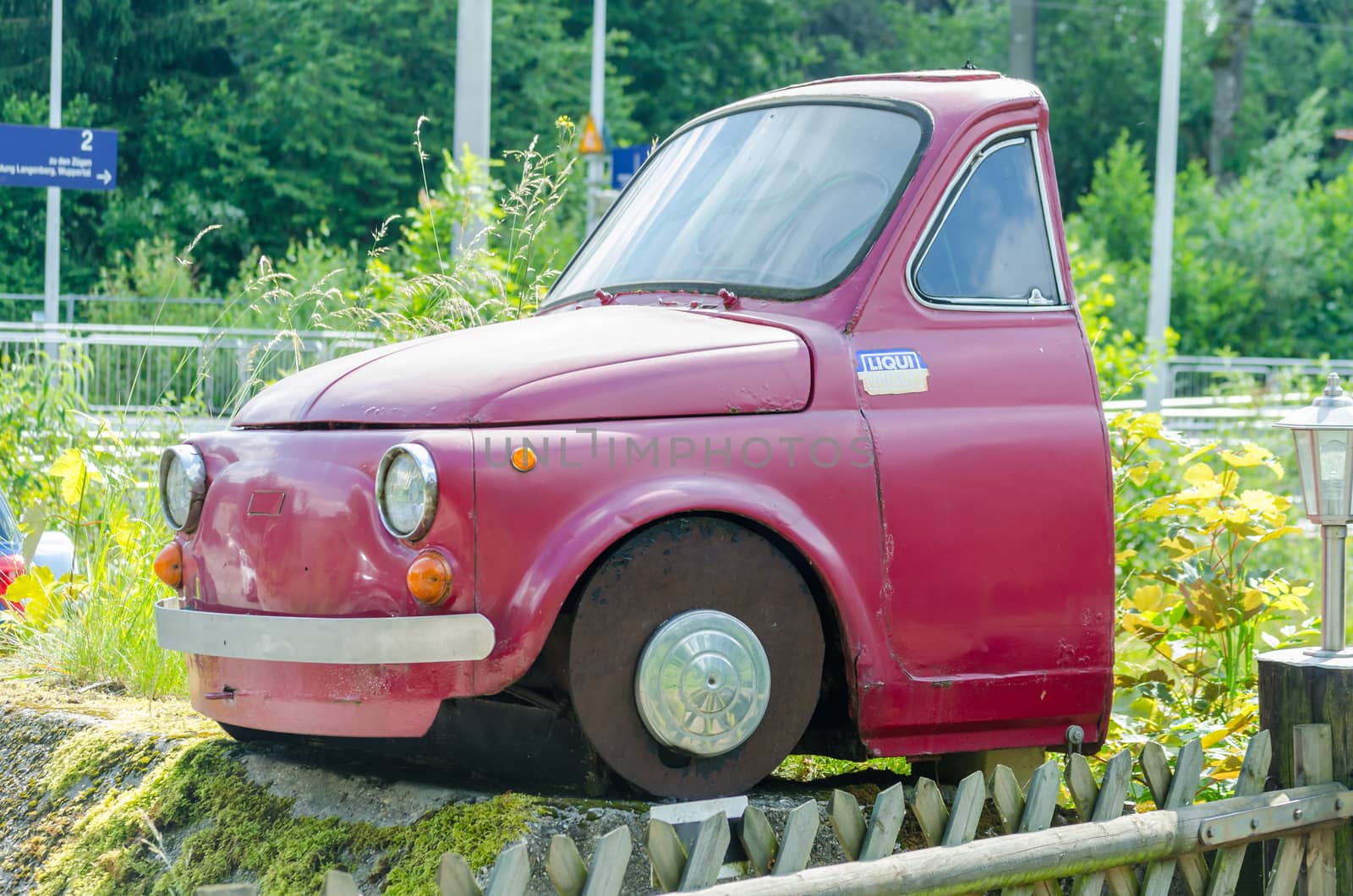 Essen, Nrw, Germany - June 13, 2014: Velber Langenberg district is that half red Fiat 500 car behind the front seats separated.
By overgrown grass. Fiat SpA is an Italian automobile manufacturer, engine manufacturer, financial and industrial group based in Turin in the Piedmont region.