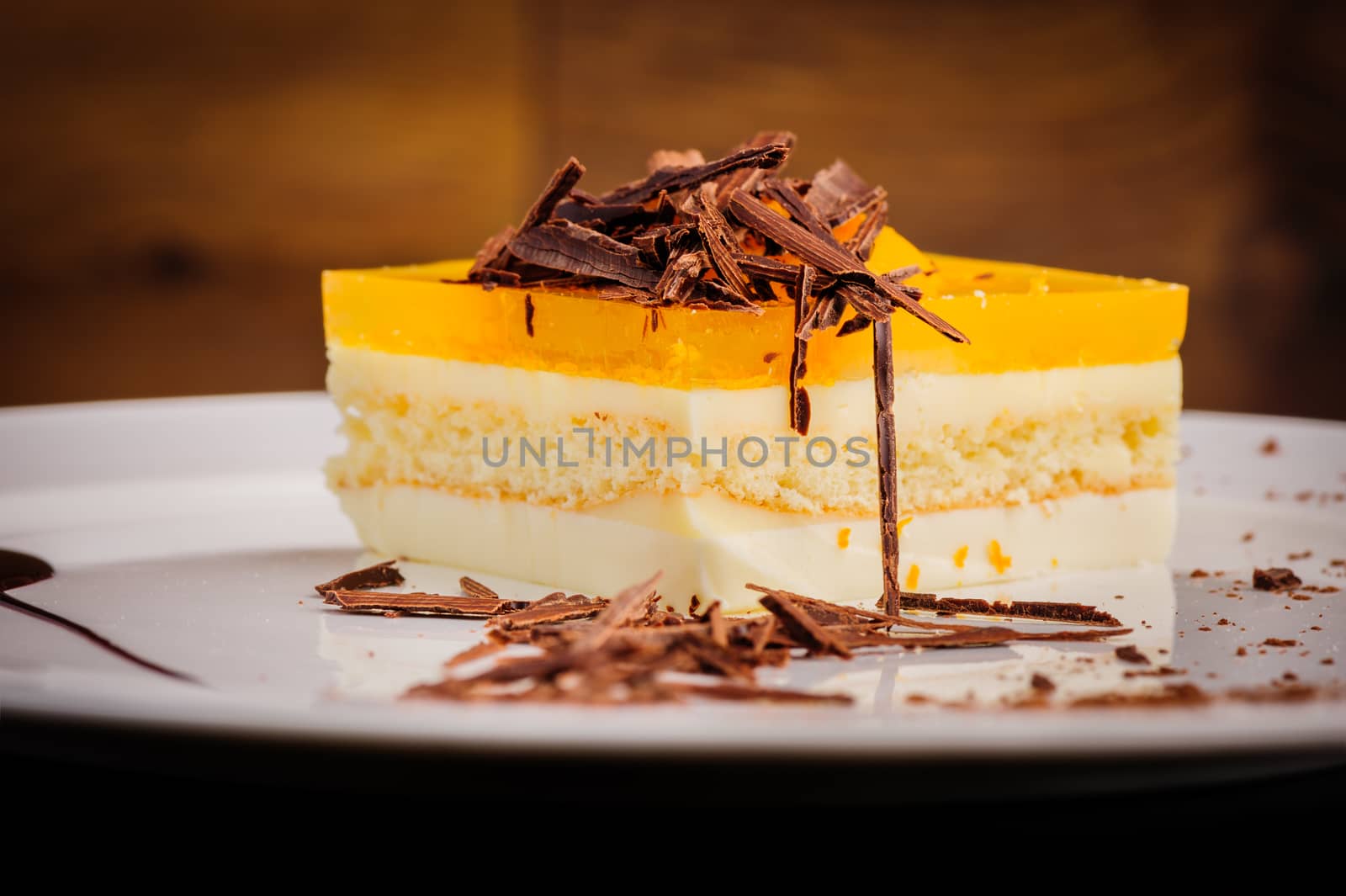 Layered delicious cheesecake with milk and orange jelly on plate