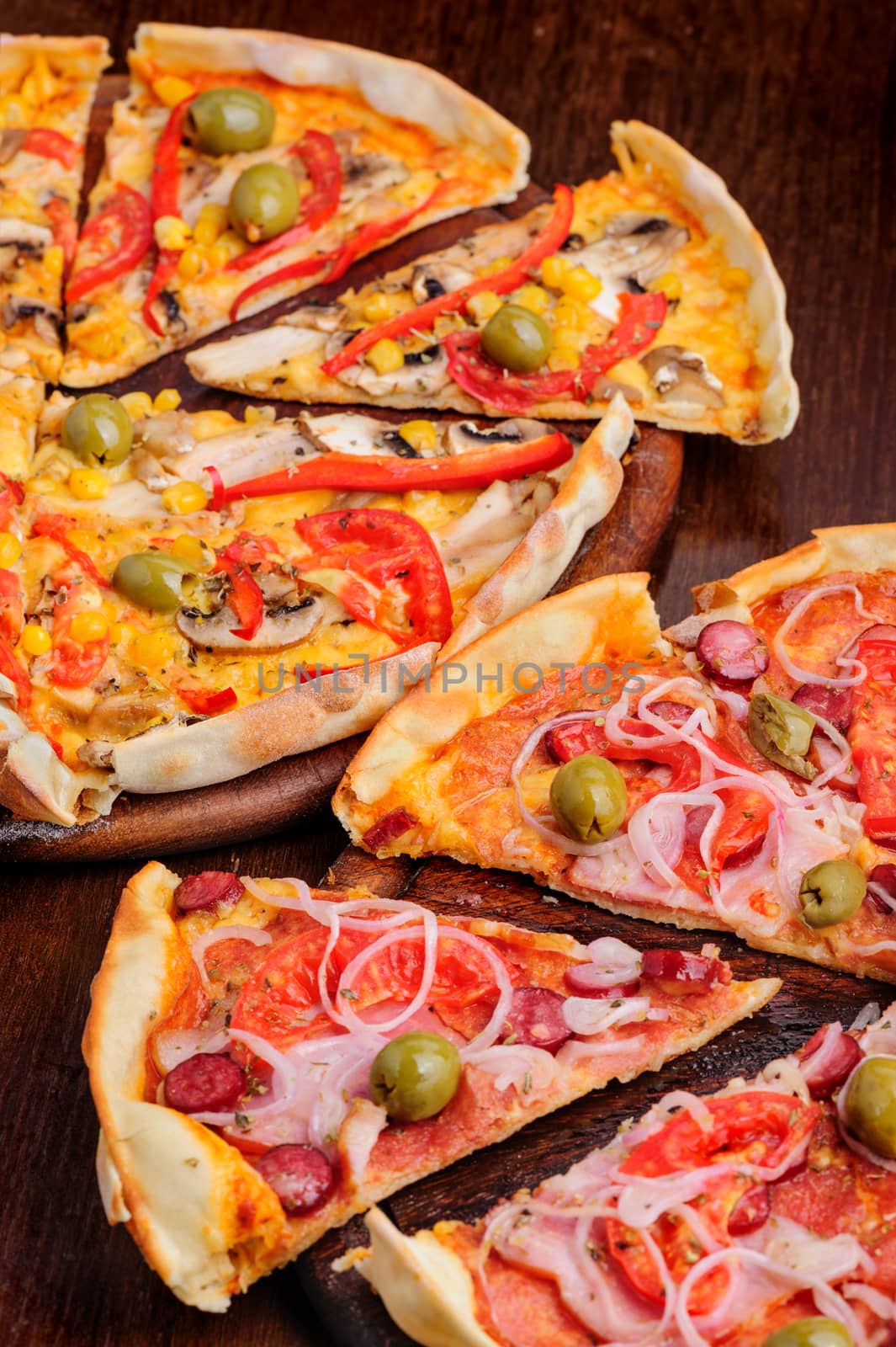 Two different pizzas with tomato, peppeeoni, olives, corn, red pepper