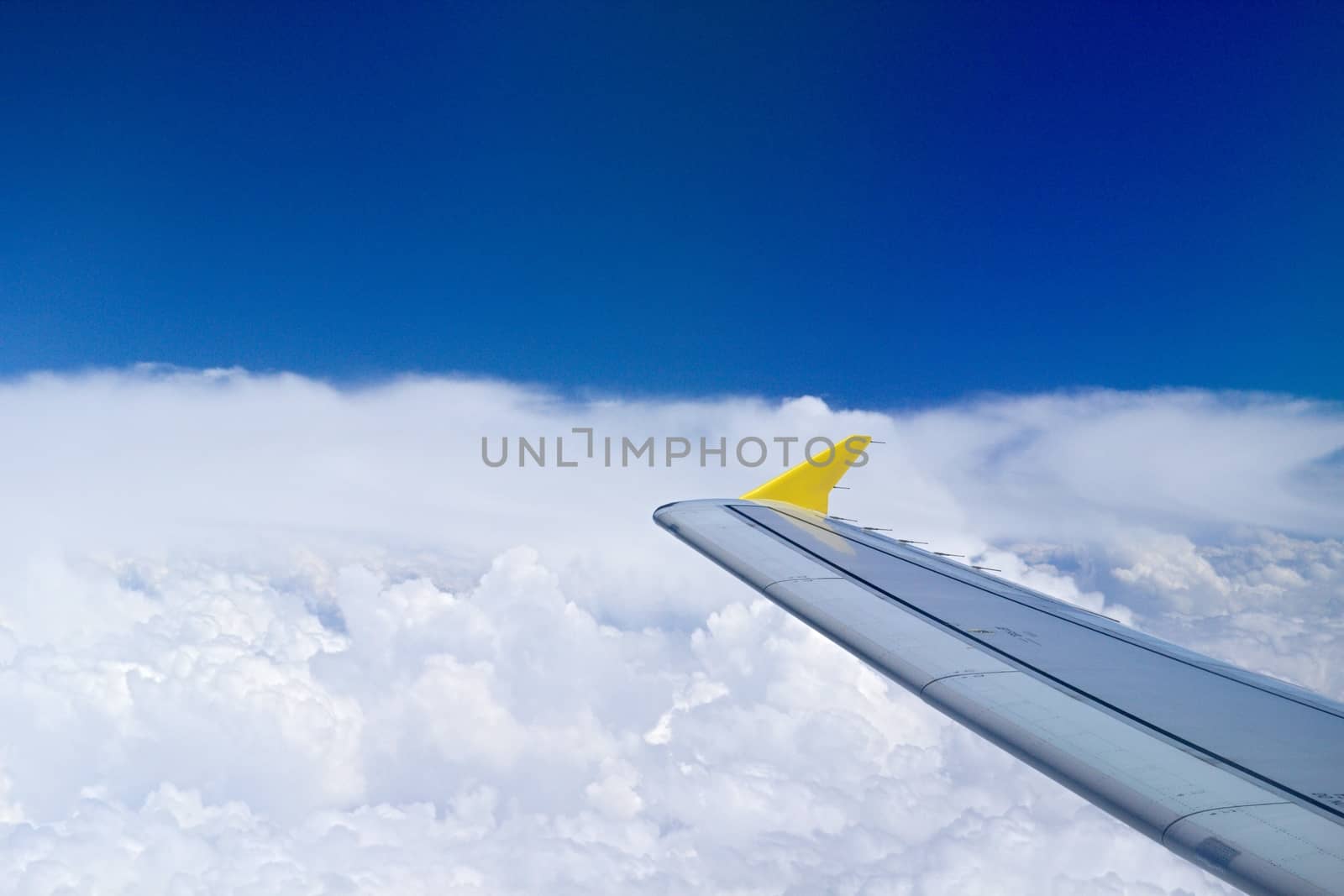 Photo shows details of white clouds, blue sky and plane.