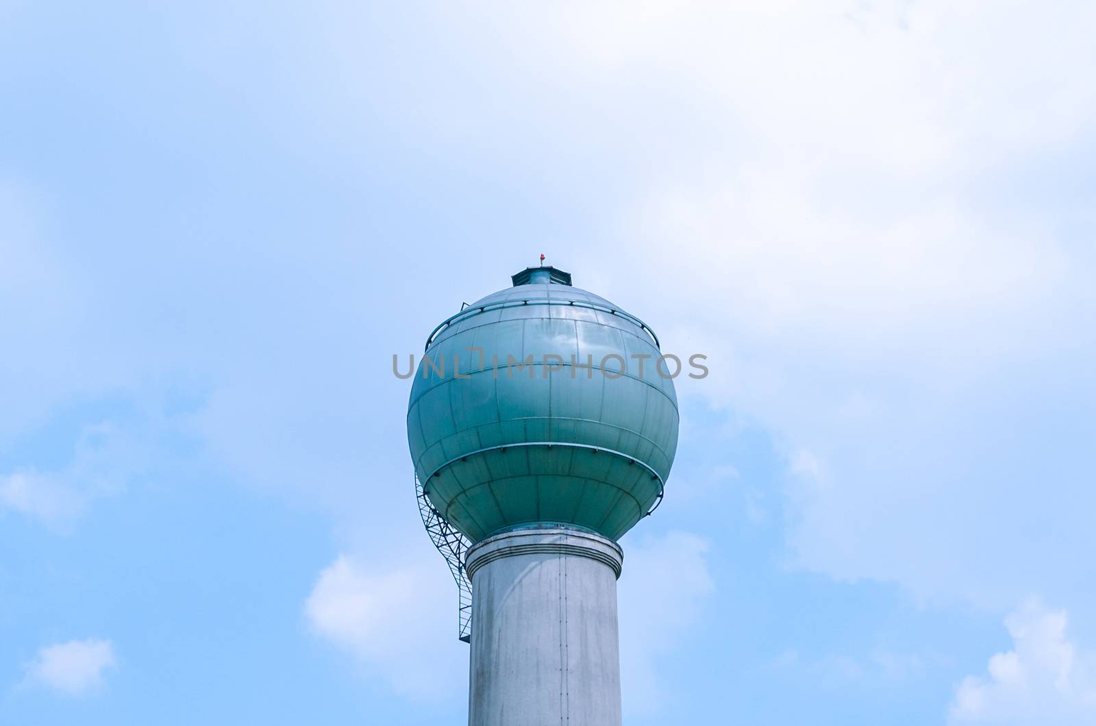 Water tower, storage tank against a blue cloudy sky easily.