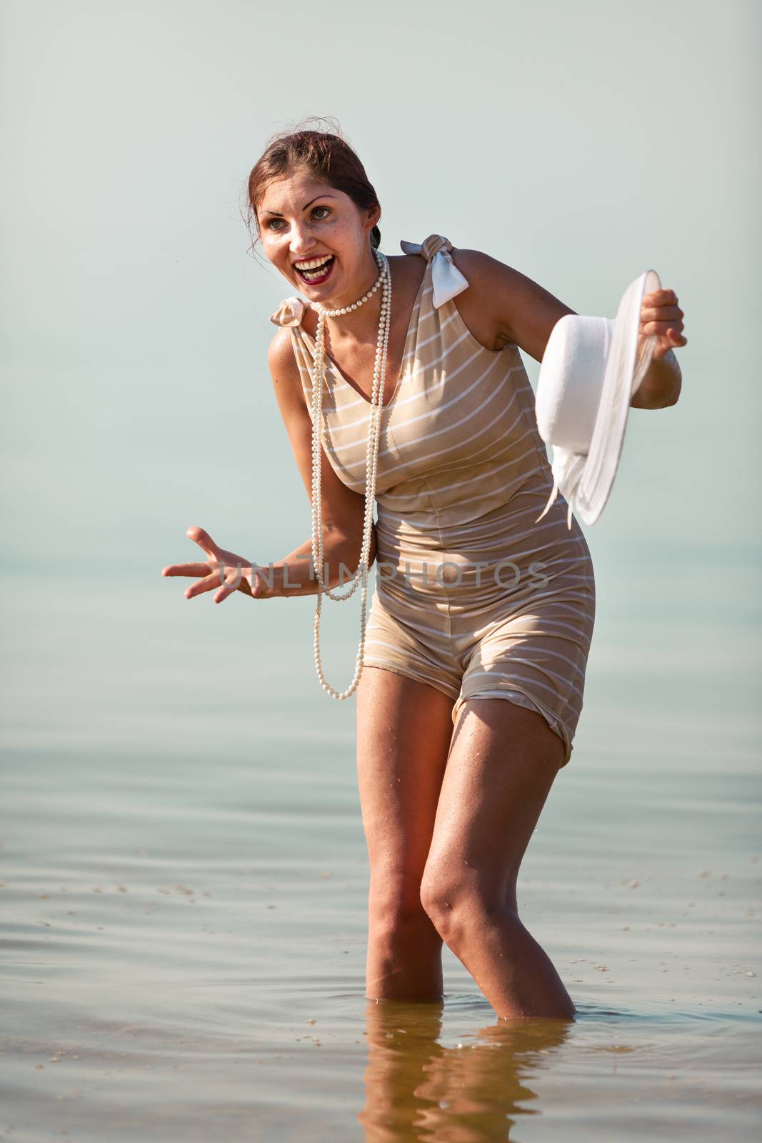 Woman in a striped retro bathing suit posing against the sea
