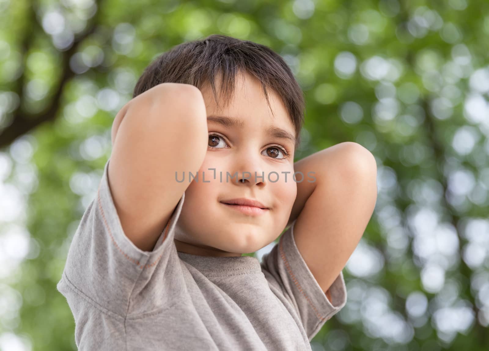 Sad little boy looking at something against blurred natural background. Focus on the eyes. Shallow DOF