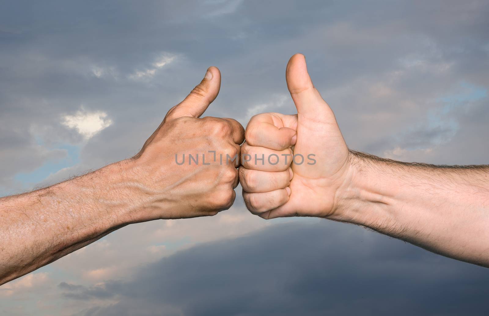 Friendship concept. Two men bumping fists with thumbs up against sky with clouds