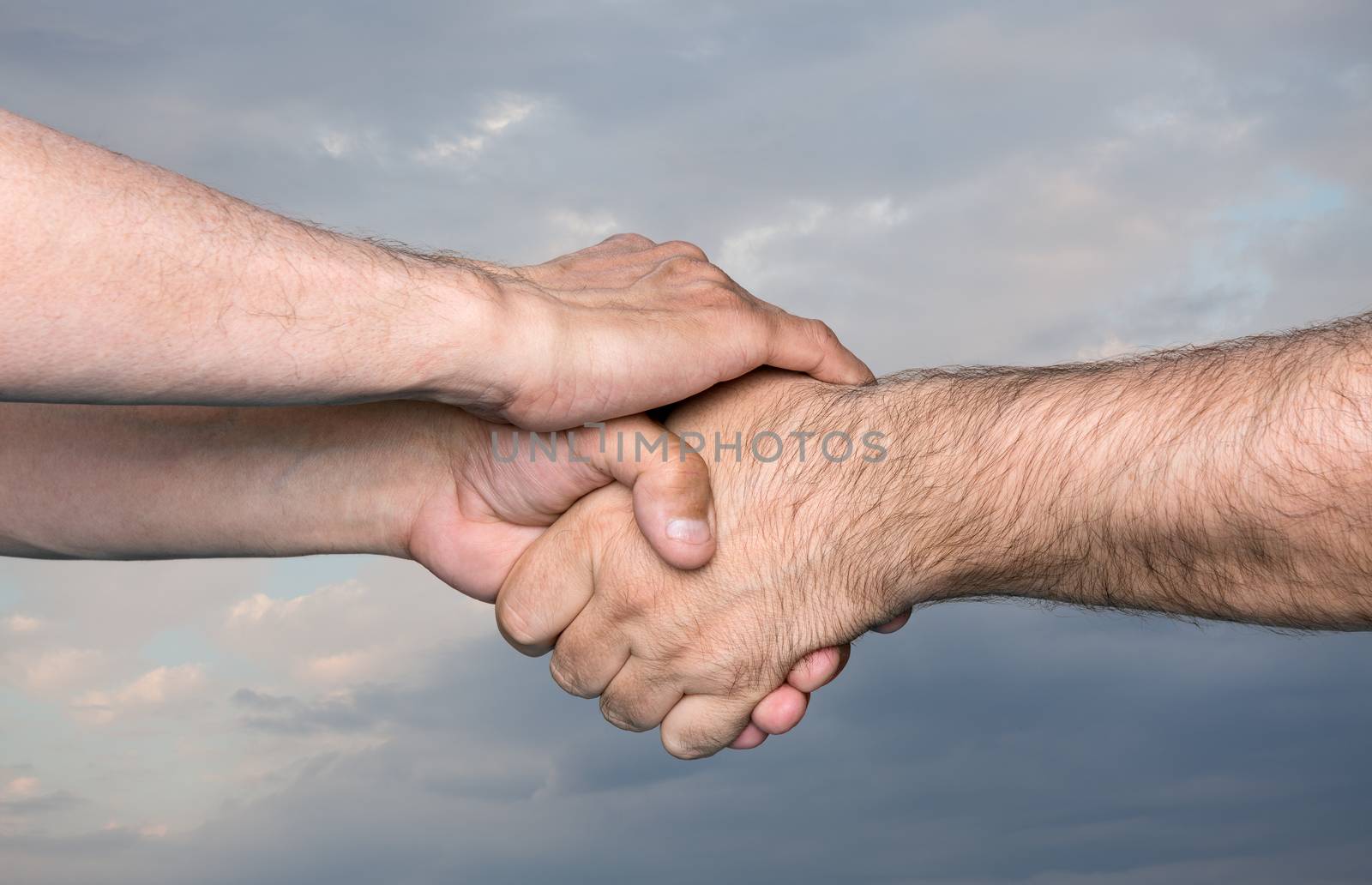Handshaking. Shaking hands of two male people against the sky with thunder clouds