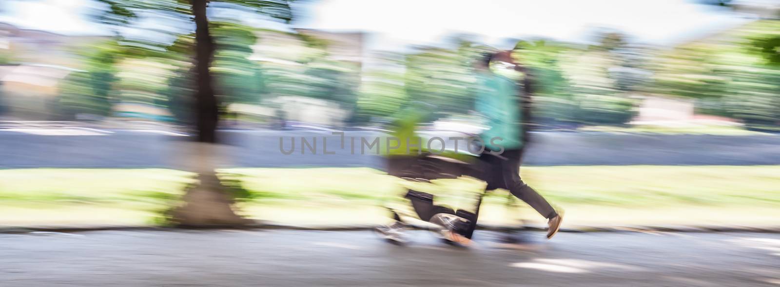 Young family with small children and a pram walking down the street. Intentional motion blur