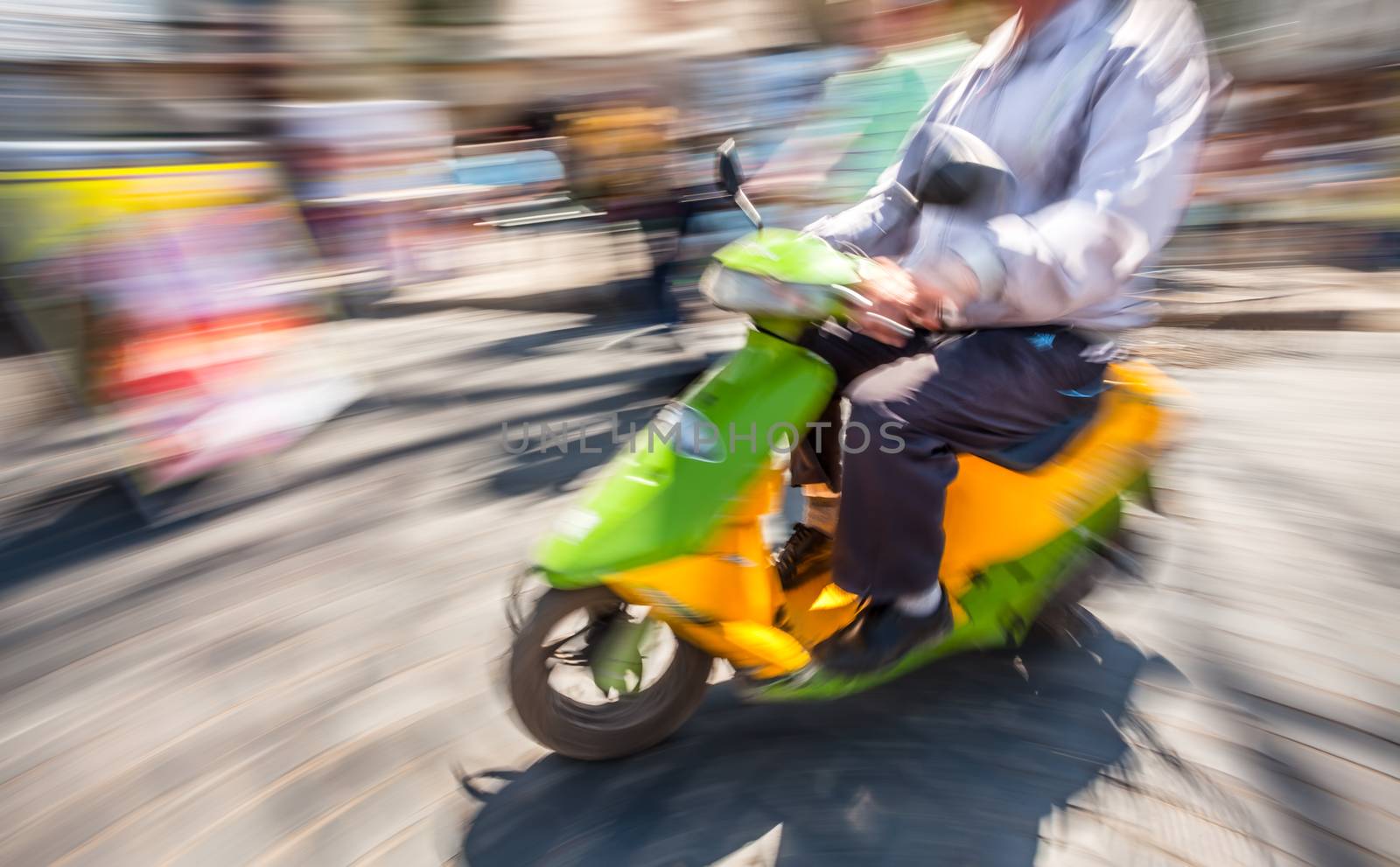 Old biker with a motorcycle in motion blur on city road in sunny day