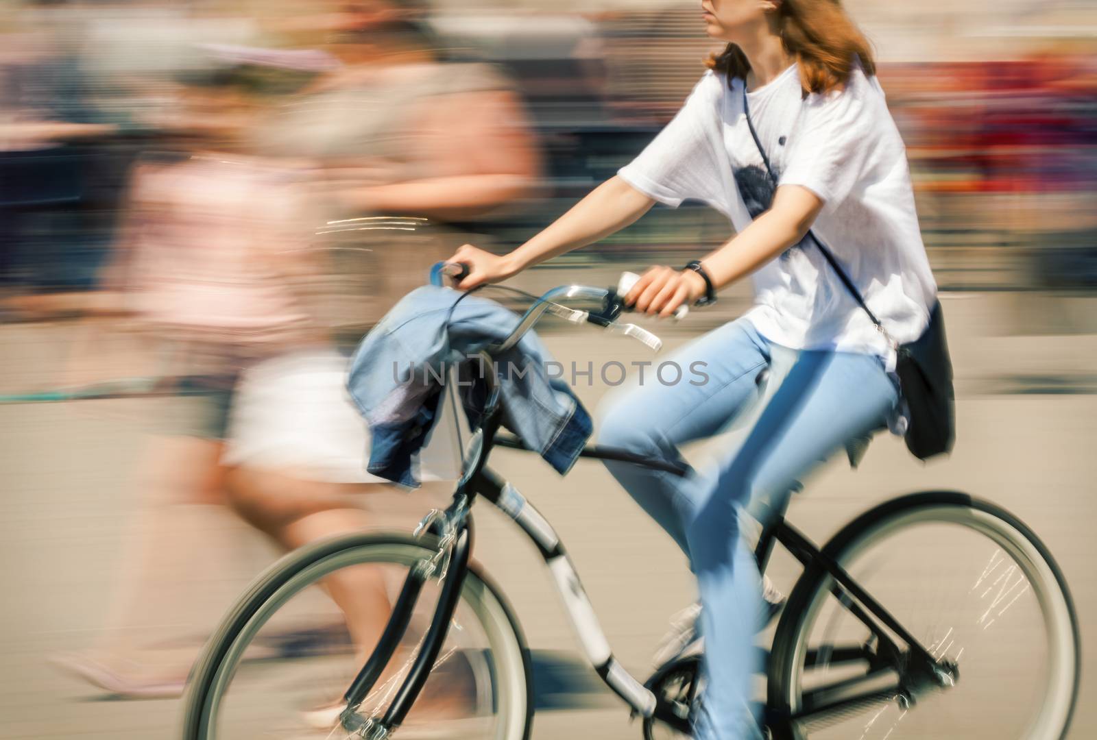 Hot day in the city. Cyclist in traffic on the city roadway. Intentional motion blur