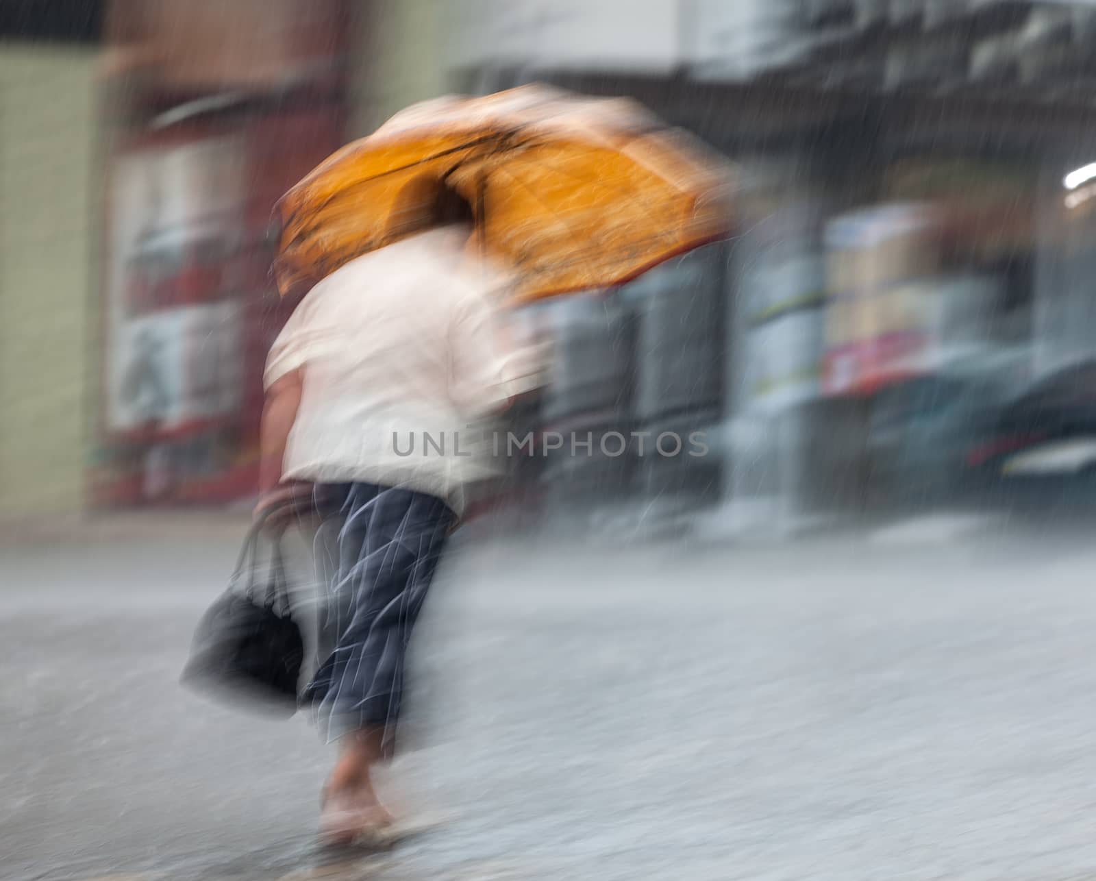 Lonely woman with umbrella walking down the street in rainy day. Intentional motion blur