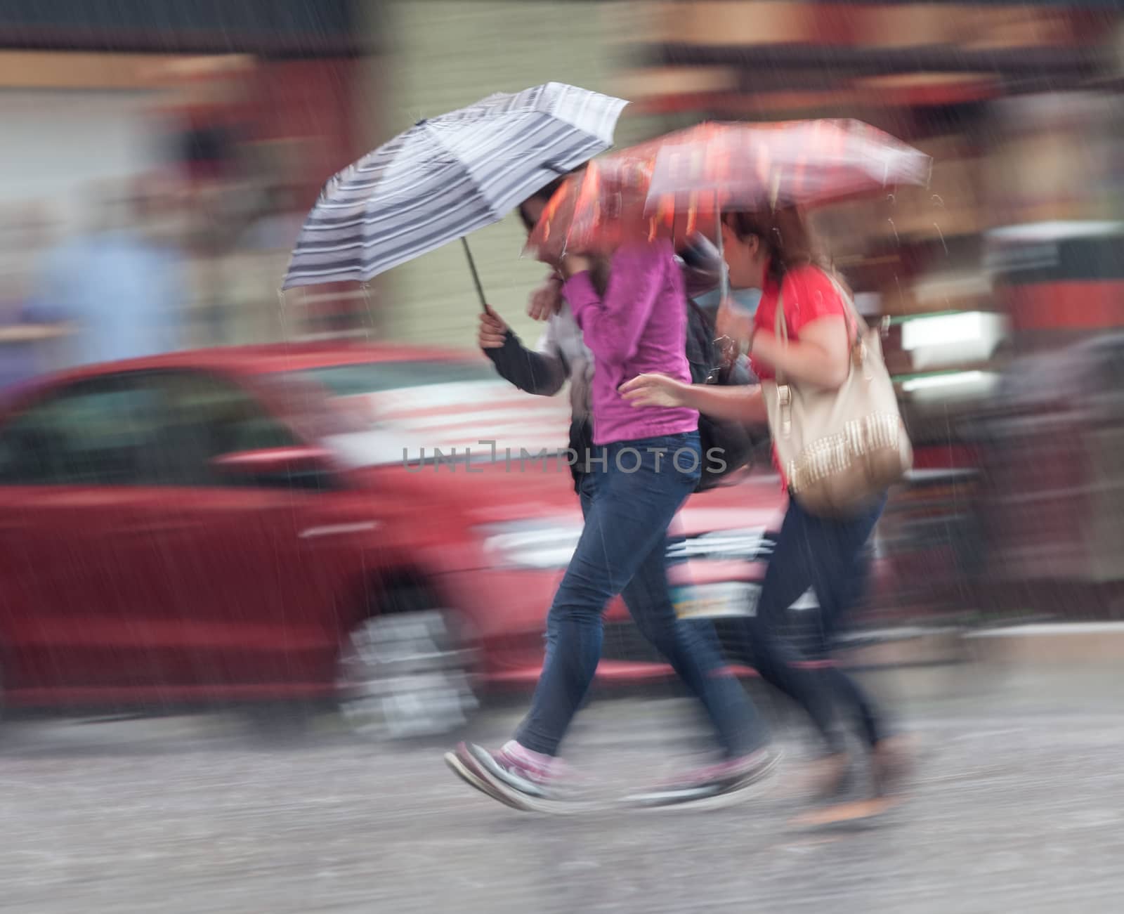 Group of young people walking down the street in rainy day. Intentional motion blur