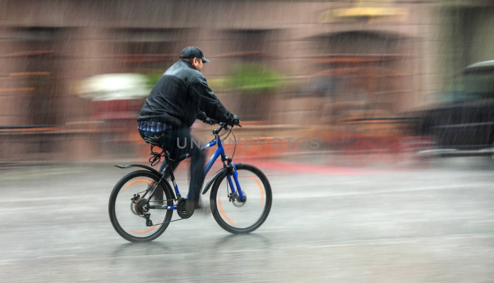 Downpour. Wet cyclist rides through the streets on a rainy day . Intentional motion blur