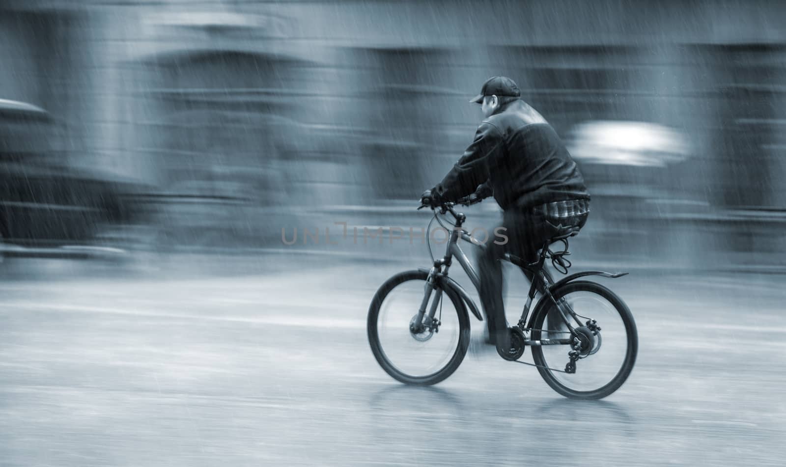 Downpour. Wet cyclist rides through the streets on a rainy day . Intentional motion blur