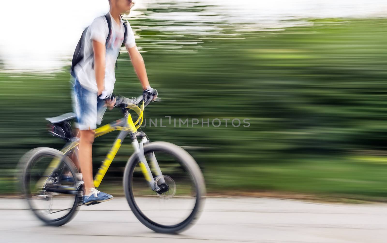 Boy cyclist in traffic on the city roadway. Intentional motion blur