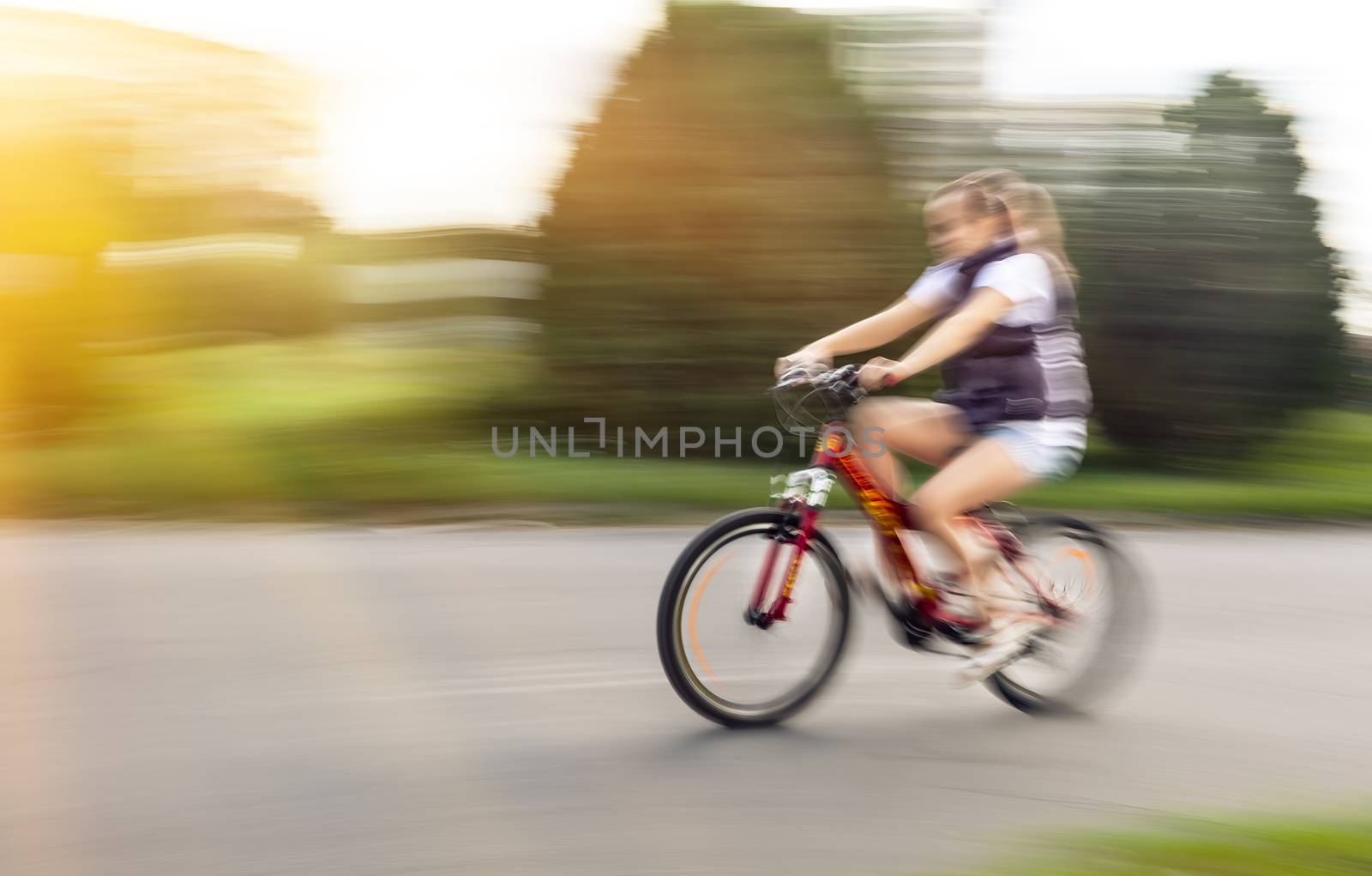 Girl cyclist in traffic on the city roadway. Intentional motion blur