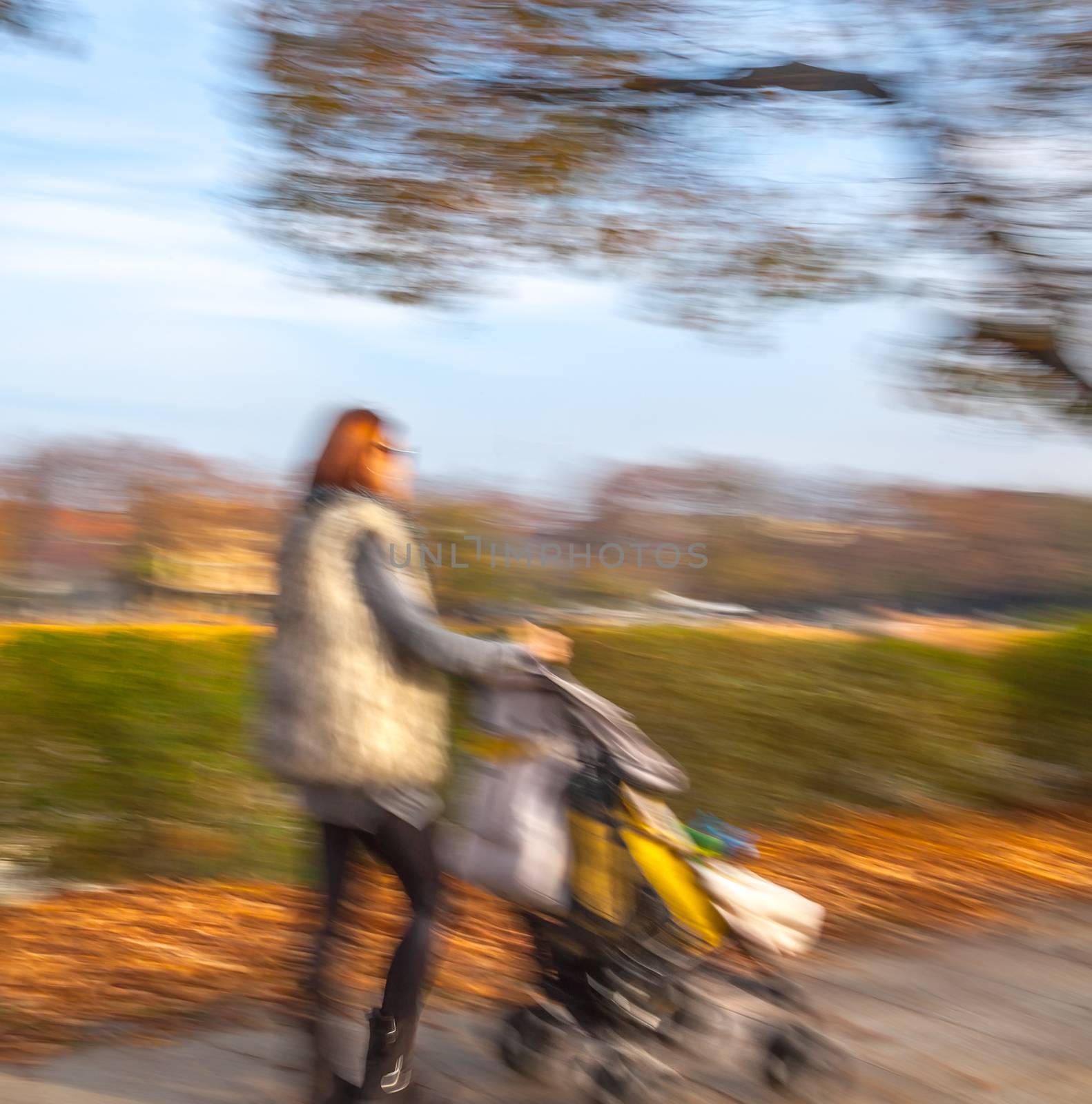 Mother with small child and a pram walking down the street. Intentional motion blur