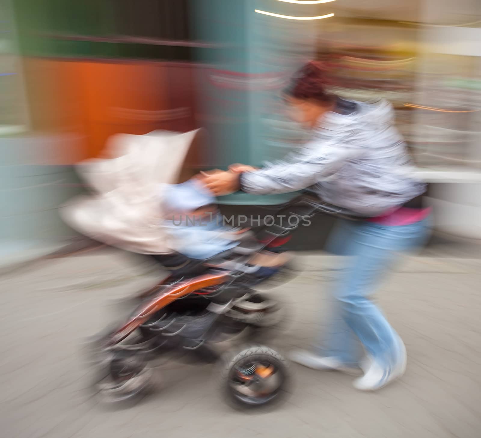 Mother with small children and a pram walking down the street. Intentional motion blur