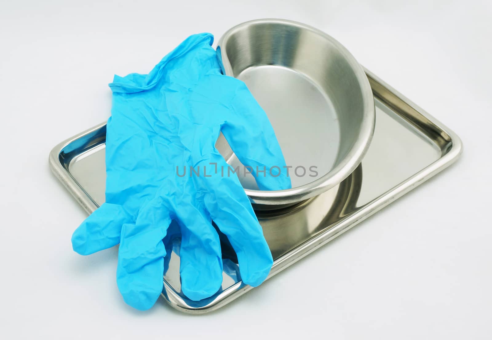 Medical devices include emesis basin tray and glove resting on a white background.                               