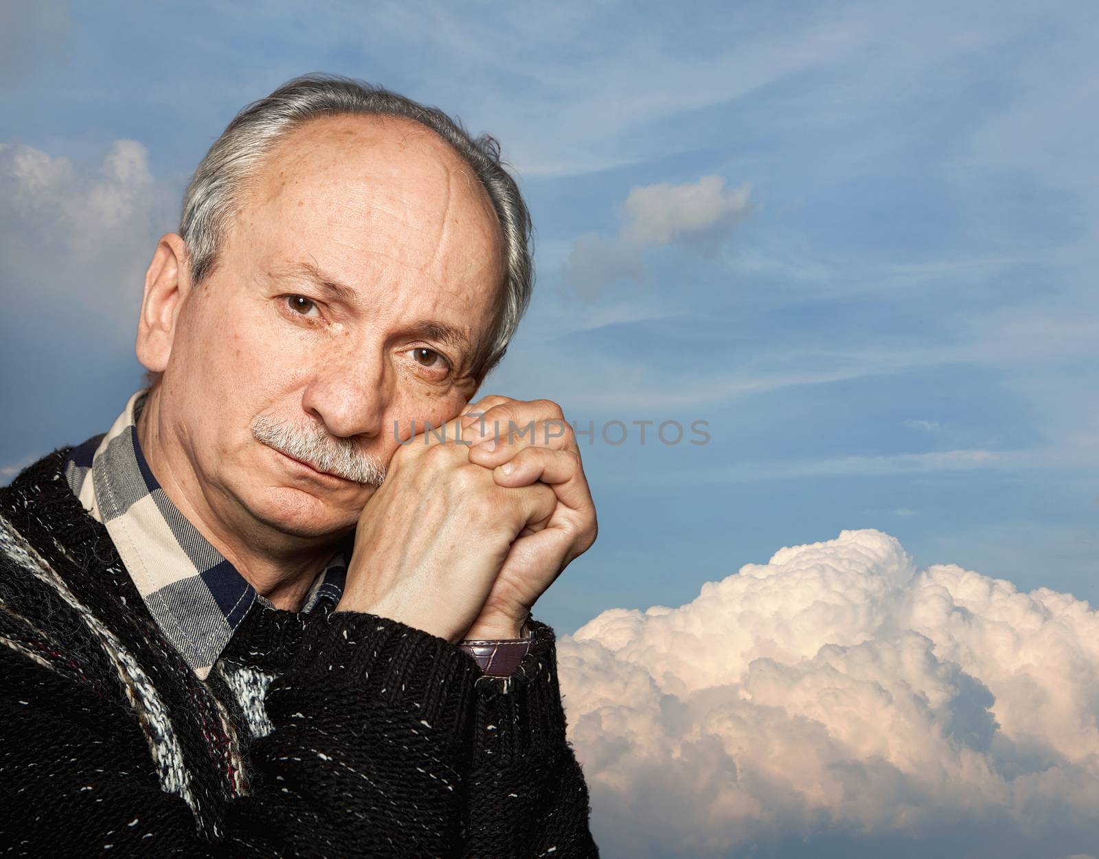 Handsome senior man with a skeptical expression against the blue sky with clouds