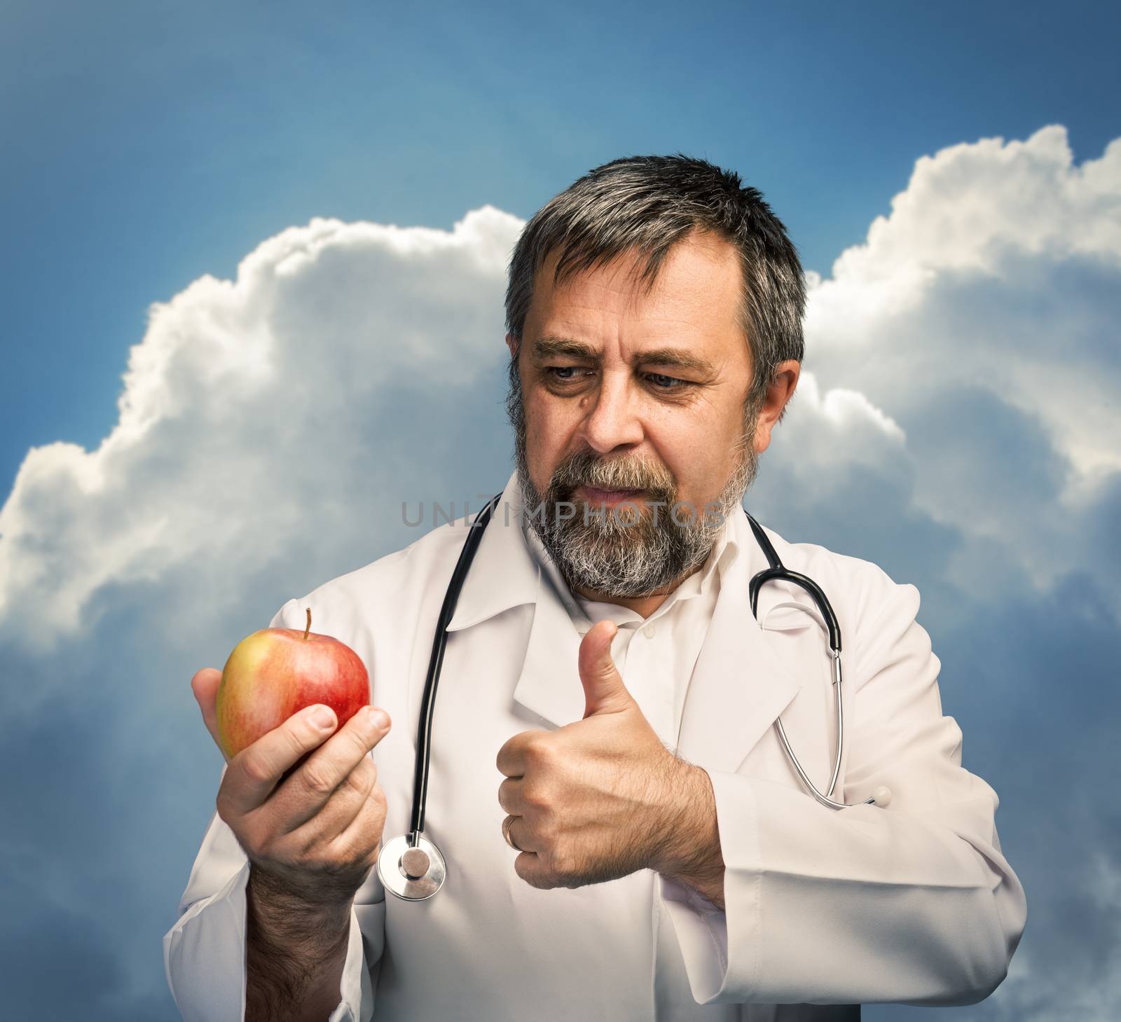 Healthy lifestyles concept. Doctor giving apple for healthy eating and lifestyle or good diet against the cloudy sky. Focus on face