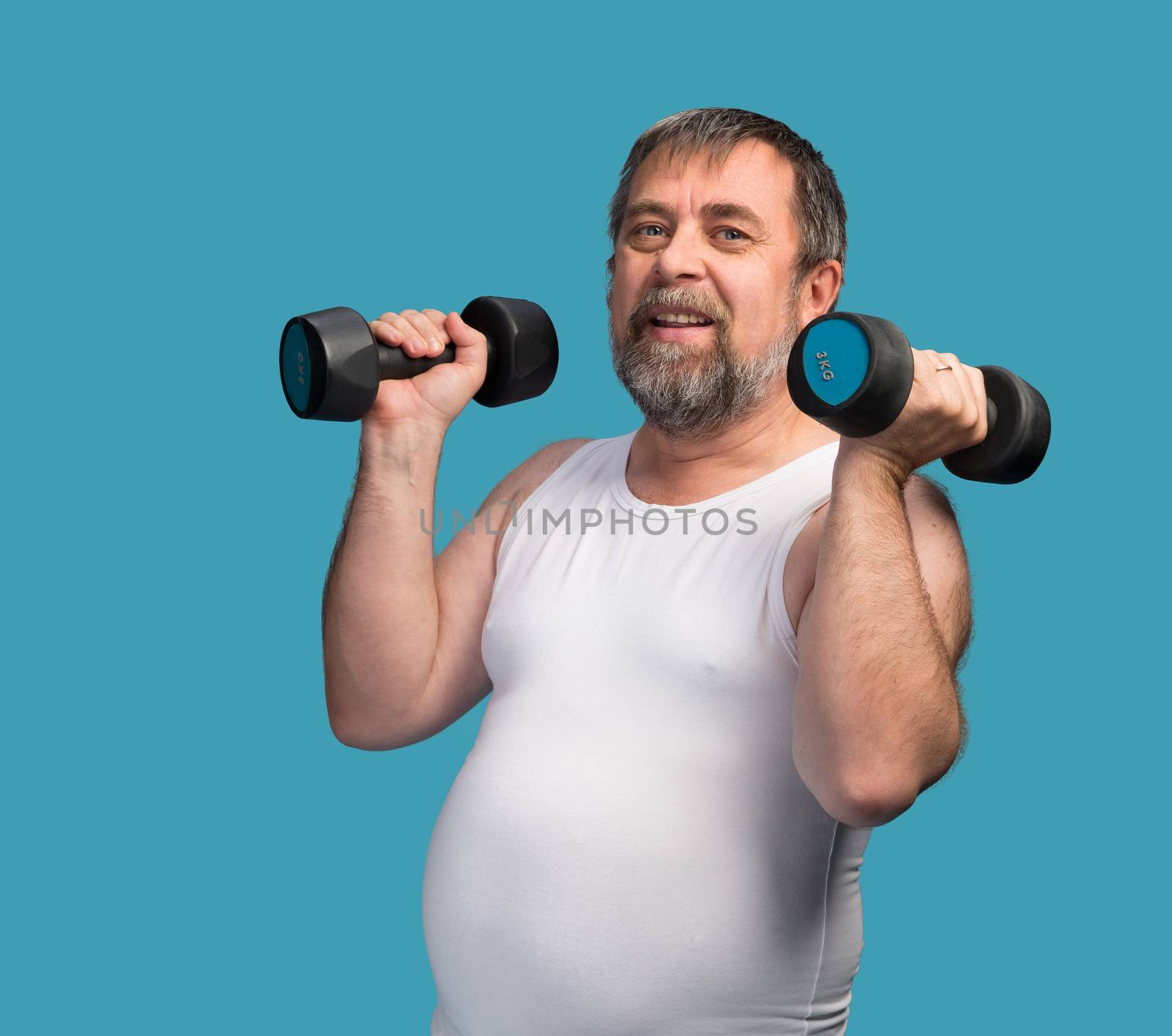 Middle-aged man with a paunch exercising with dumbbells on blue background