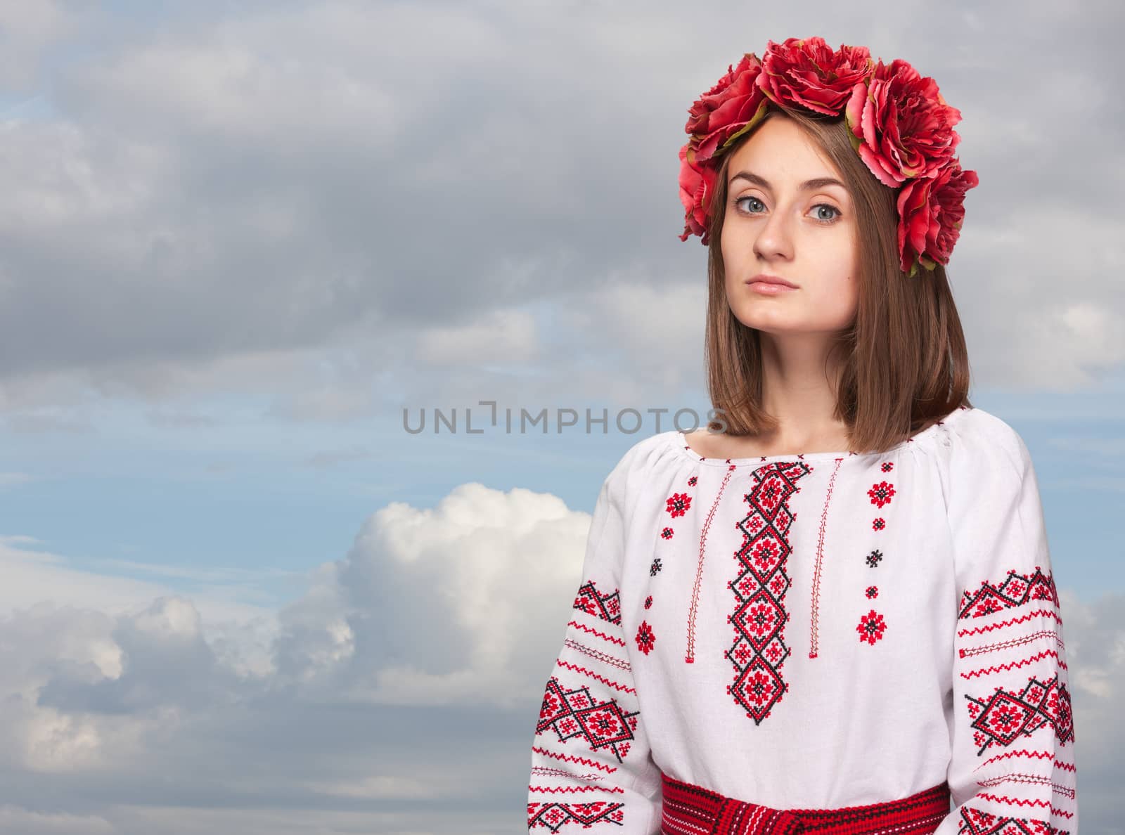 Beautiful sad girl in the Ukrainian national suit against the cloudy sky
