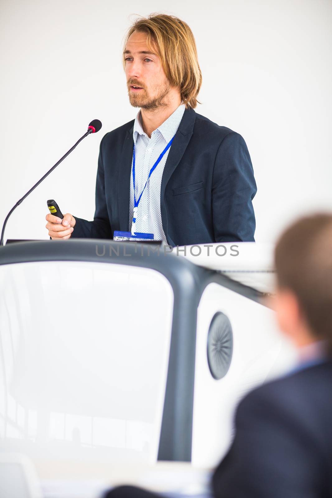 Handsome young man giving a speech at a conference by viktor_cap