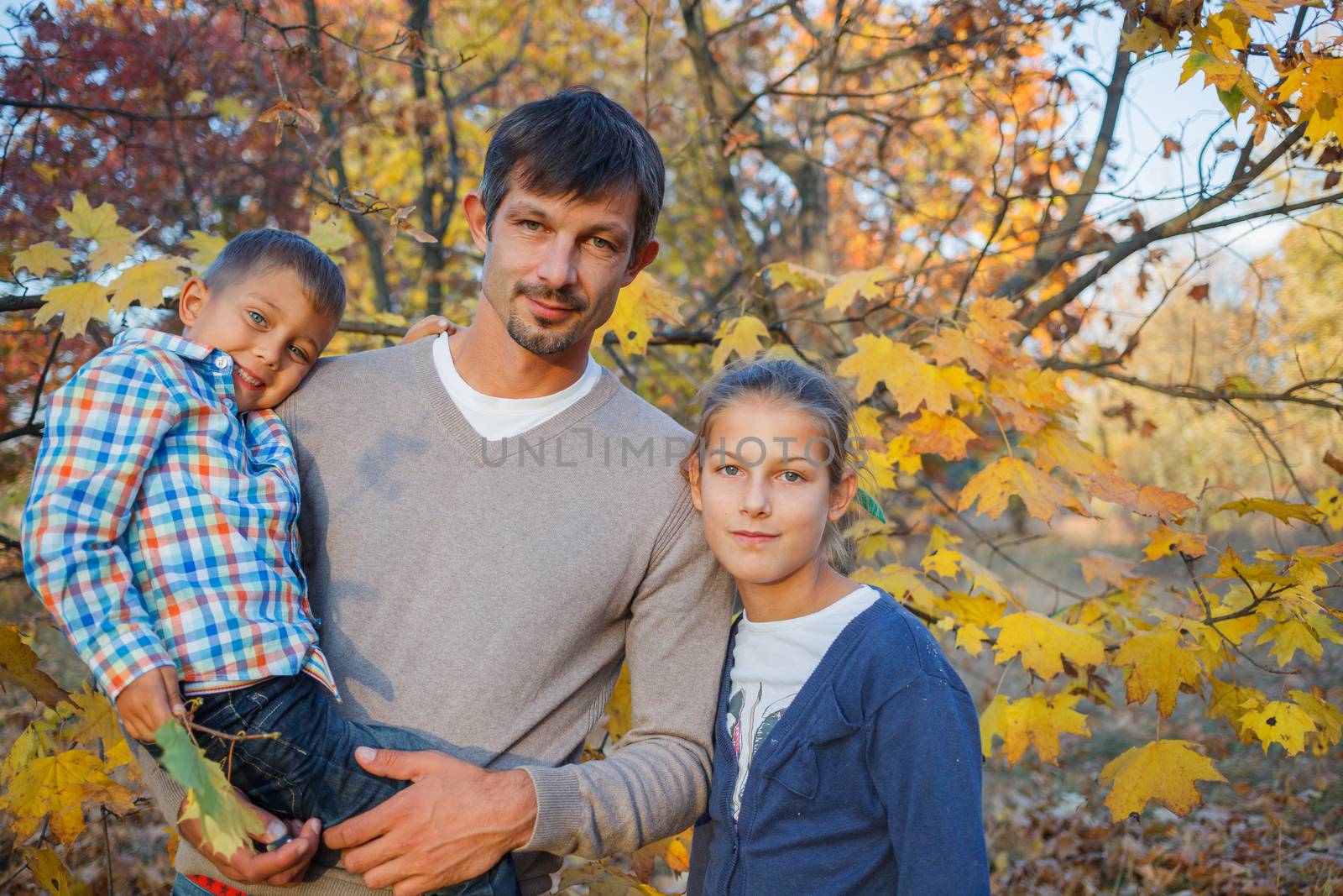 Happy family relaxing in autumn park - father with his kids has fun in park.