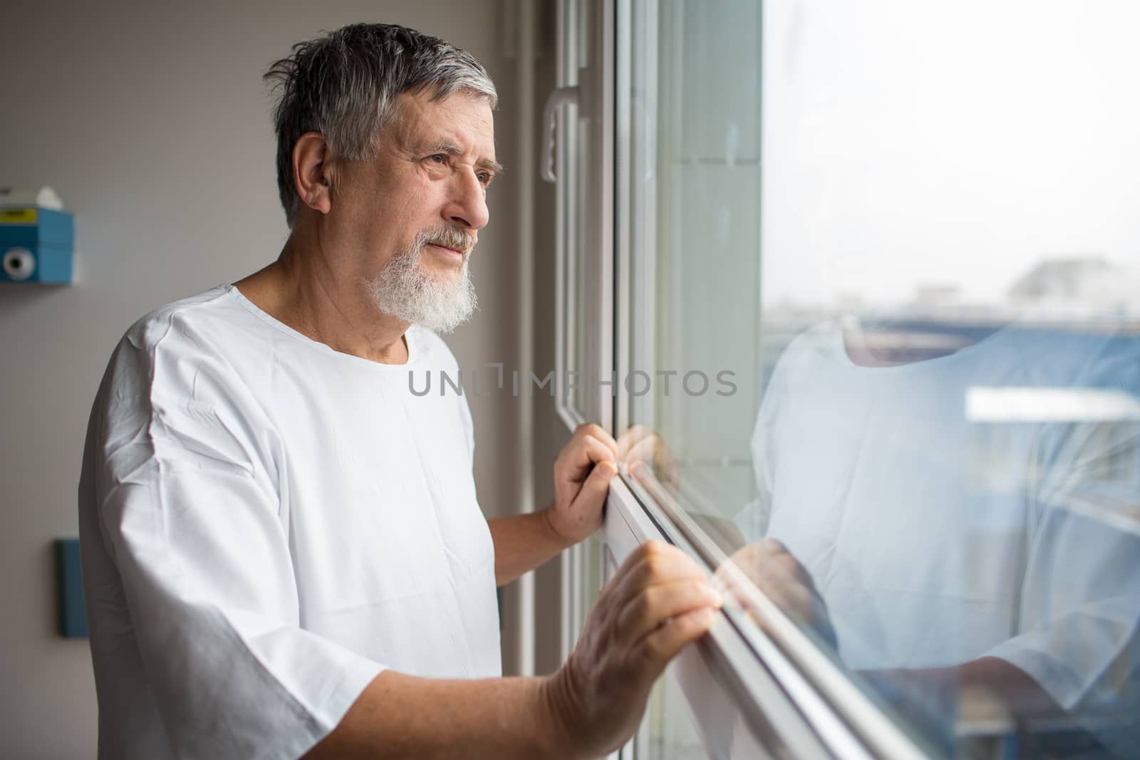 Patient at a hospital, looking from a window in his room, doing much better after the surgery