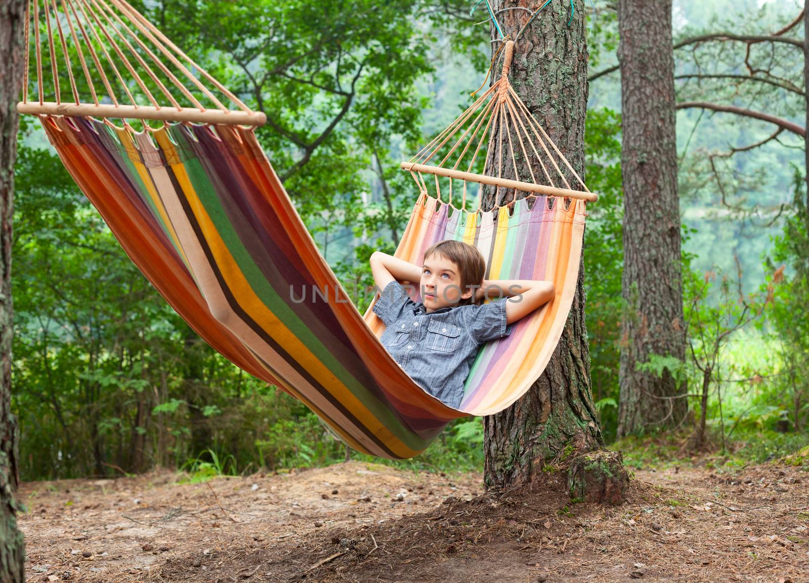 Serene boy lying in striped hammock outdoors