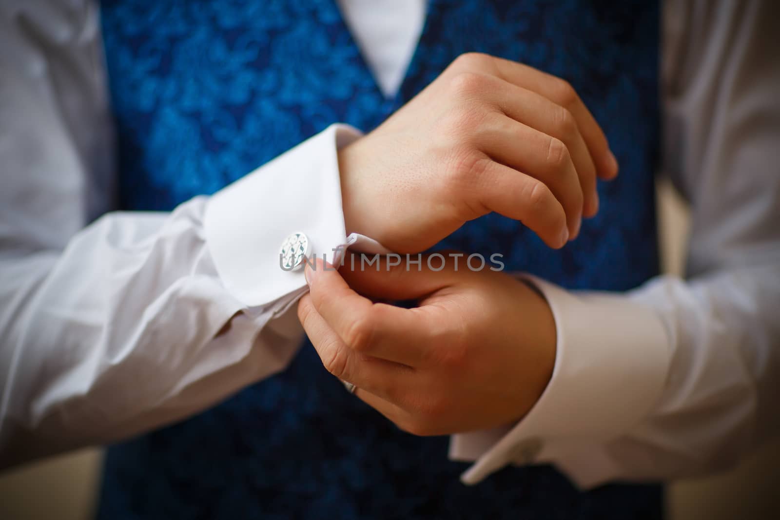 Bridegroom preparing for the wedding, straightens his shirt sleeves