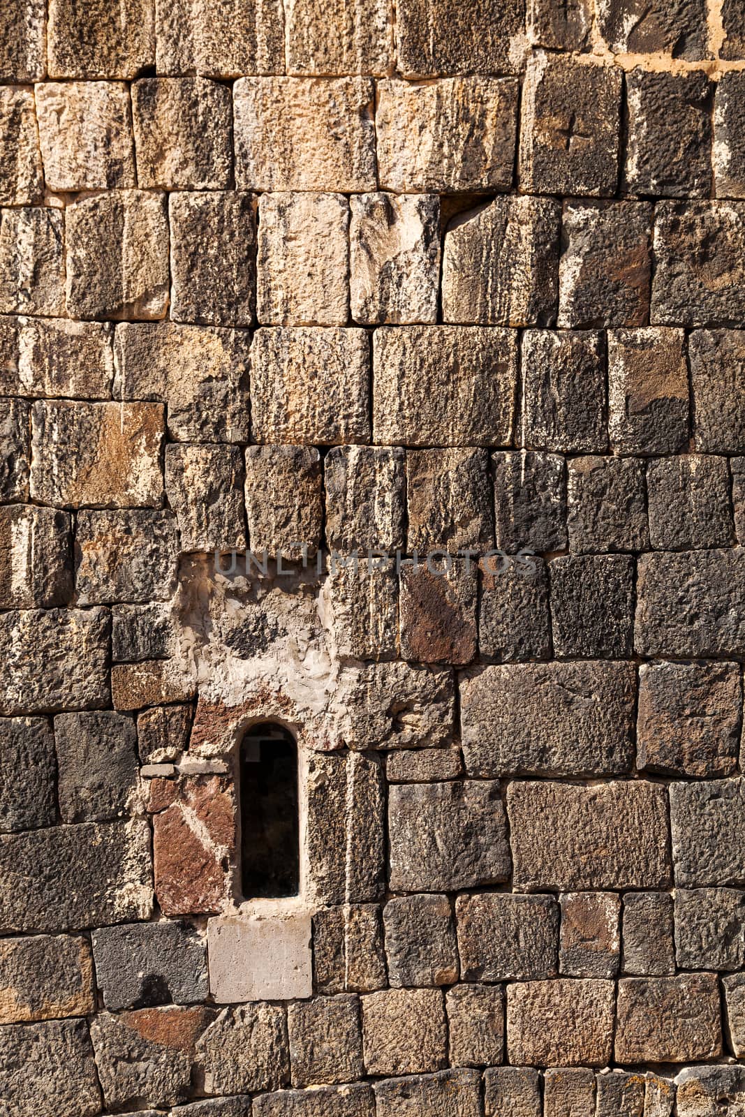 fragment of a stone wall with a malyenky window, a vertical shot