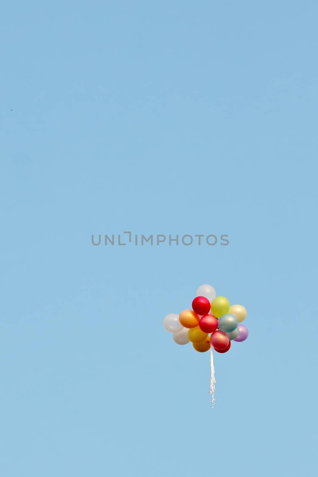 Lost bunch of painted balloons in a blue sky flying away