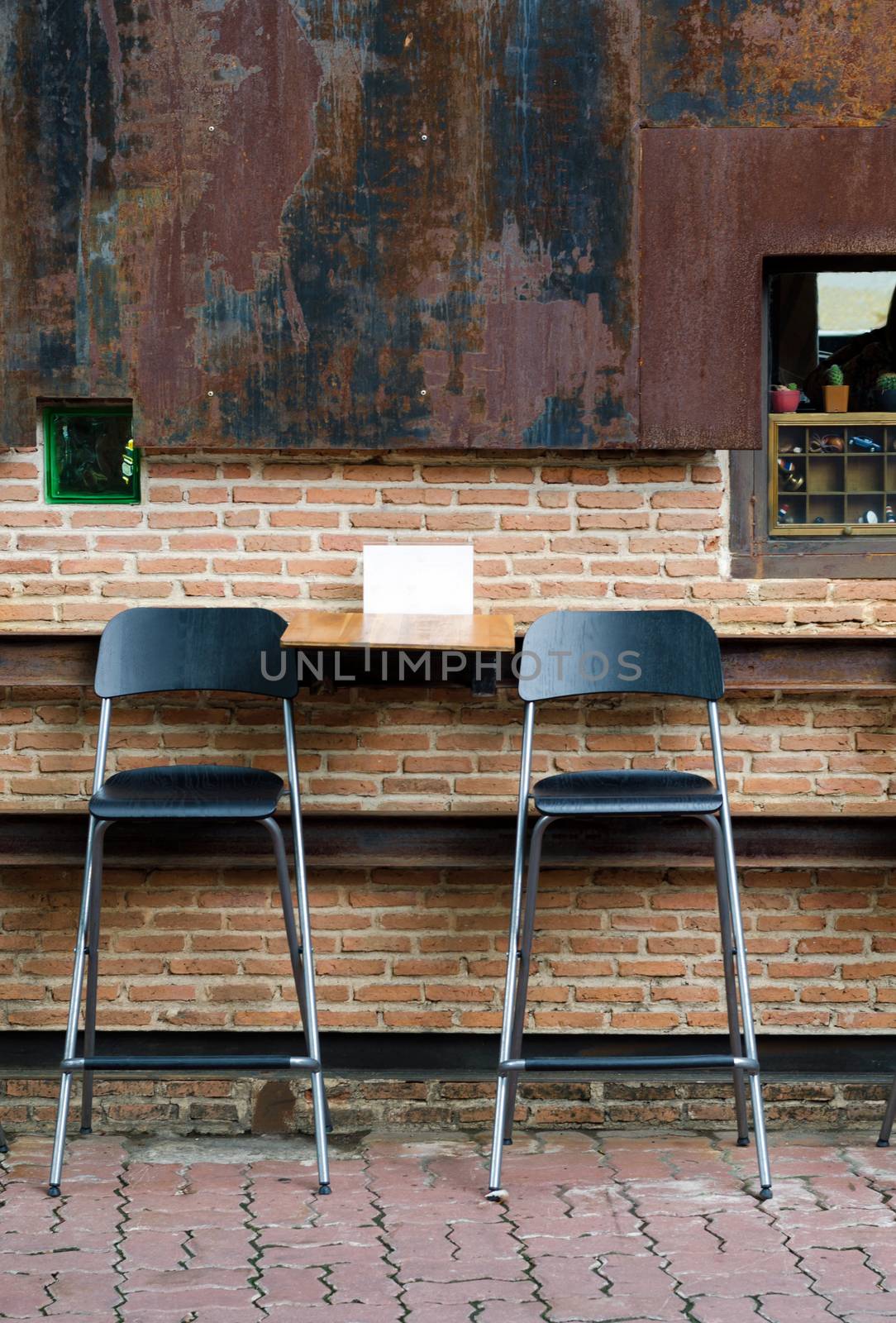 Two cafe chairs against brick wall by siraanamwong