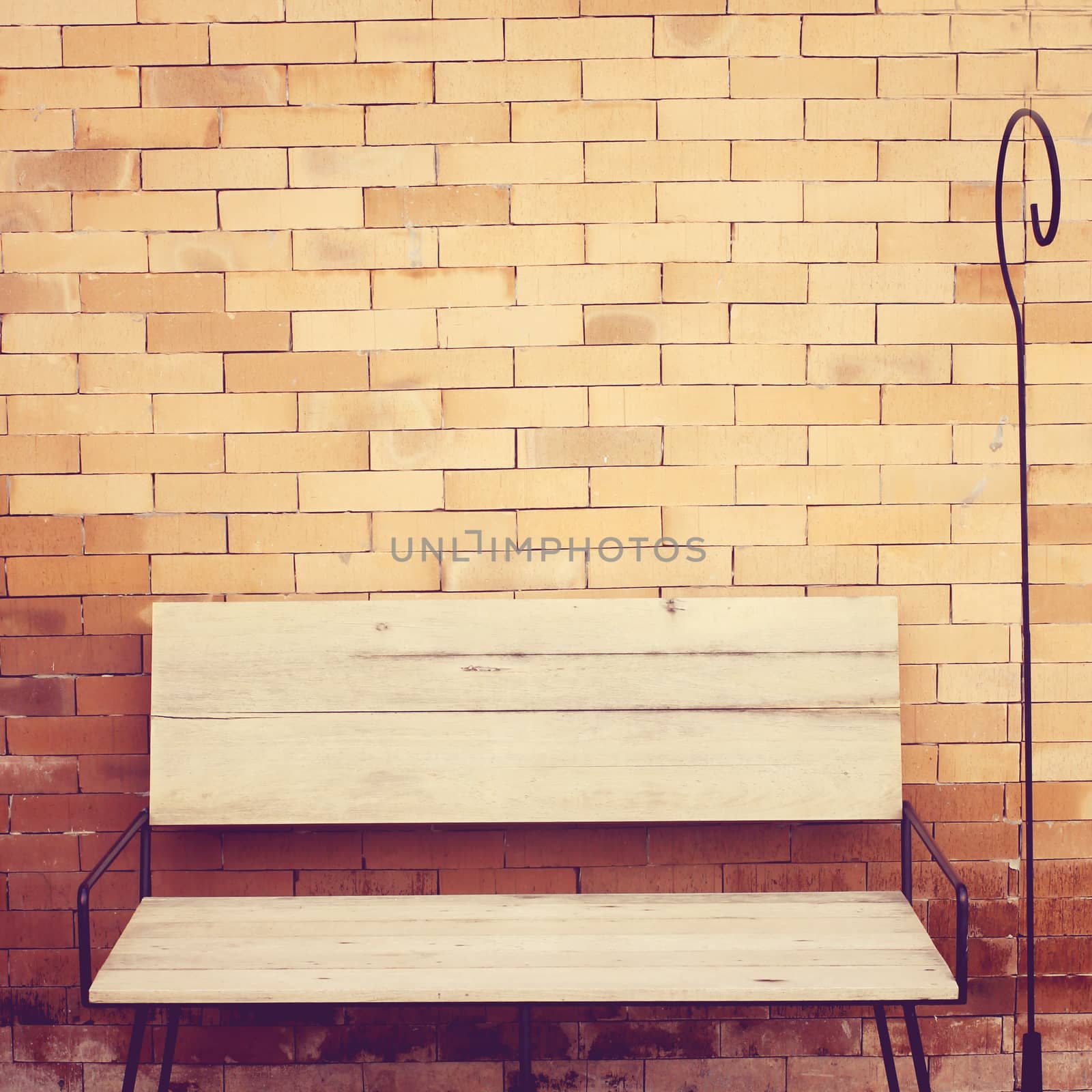 Outdoor wooden chair on brick wall, retro filter effect  by nuchylee