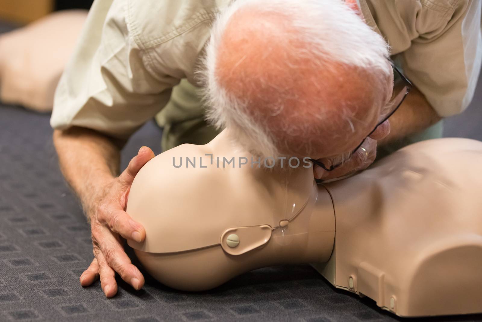 Seniror first aid student practitcing CPR on a dummy. 