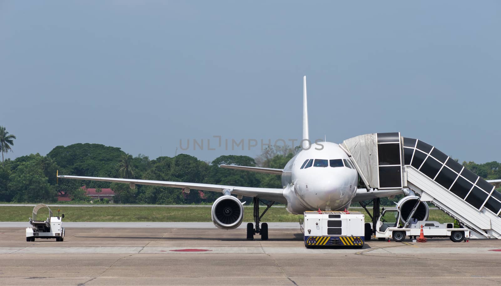 Two engine passenger jet airplane and airport vehicles at airport.