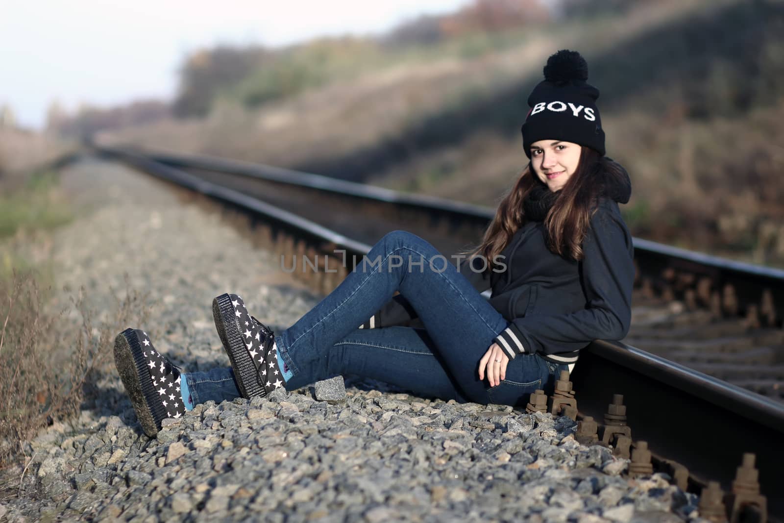 A girl sitting near the railway at sunset